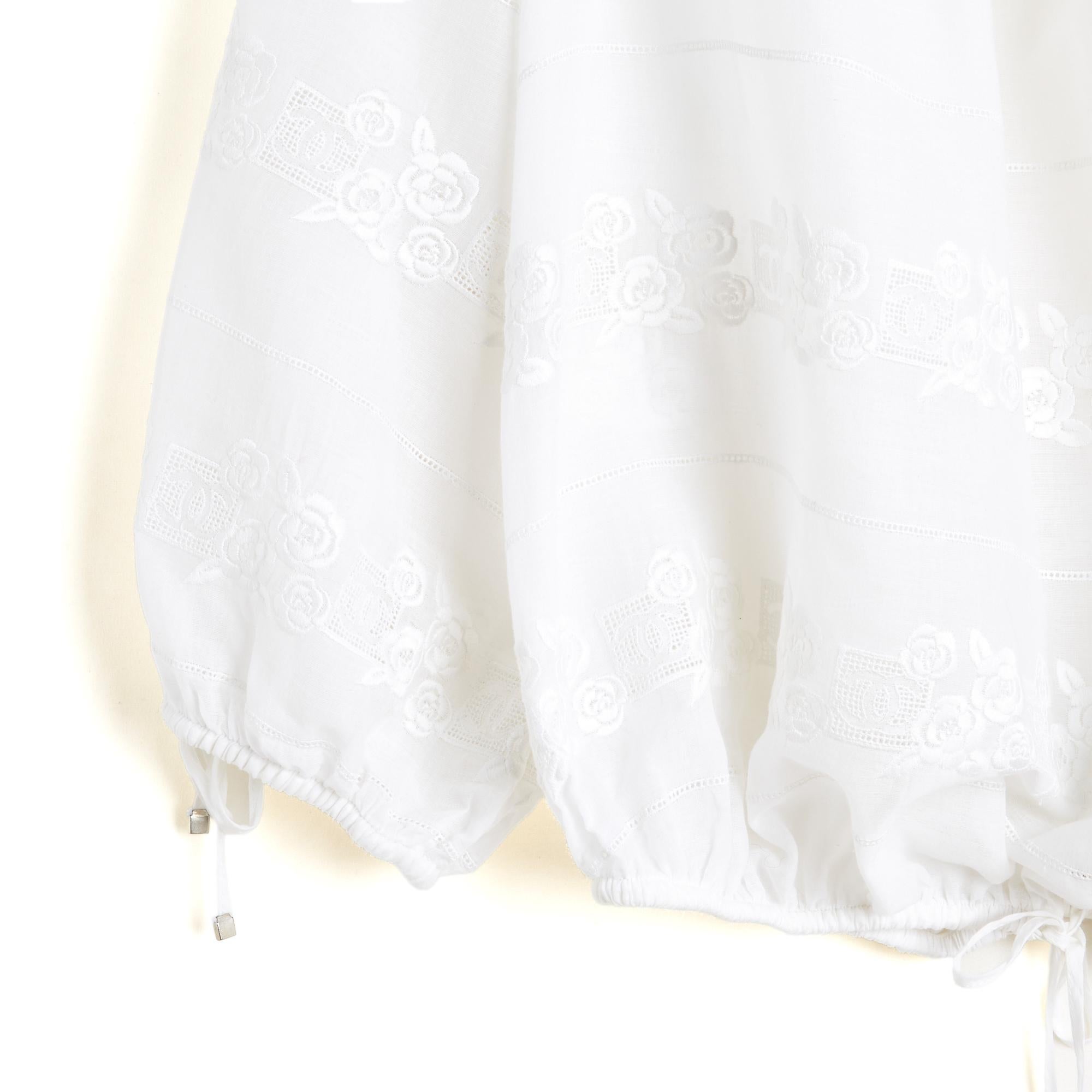 Blusa Chanel de la colección SS2007 de Karl Lagerfeld en voile de algodón blanco, amplio cuello barco elástico decorado con 2 pequeños lazos, parte inferior ajustada con una banda elástica y 2 lazos para anudar, mangas raglán largas ajustadas con