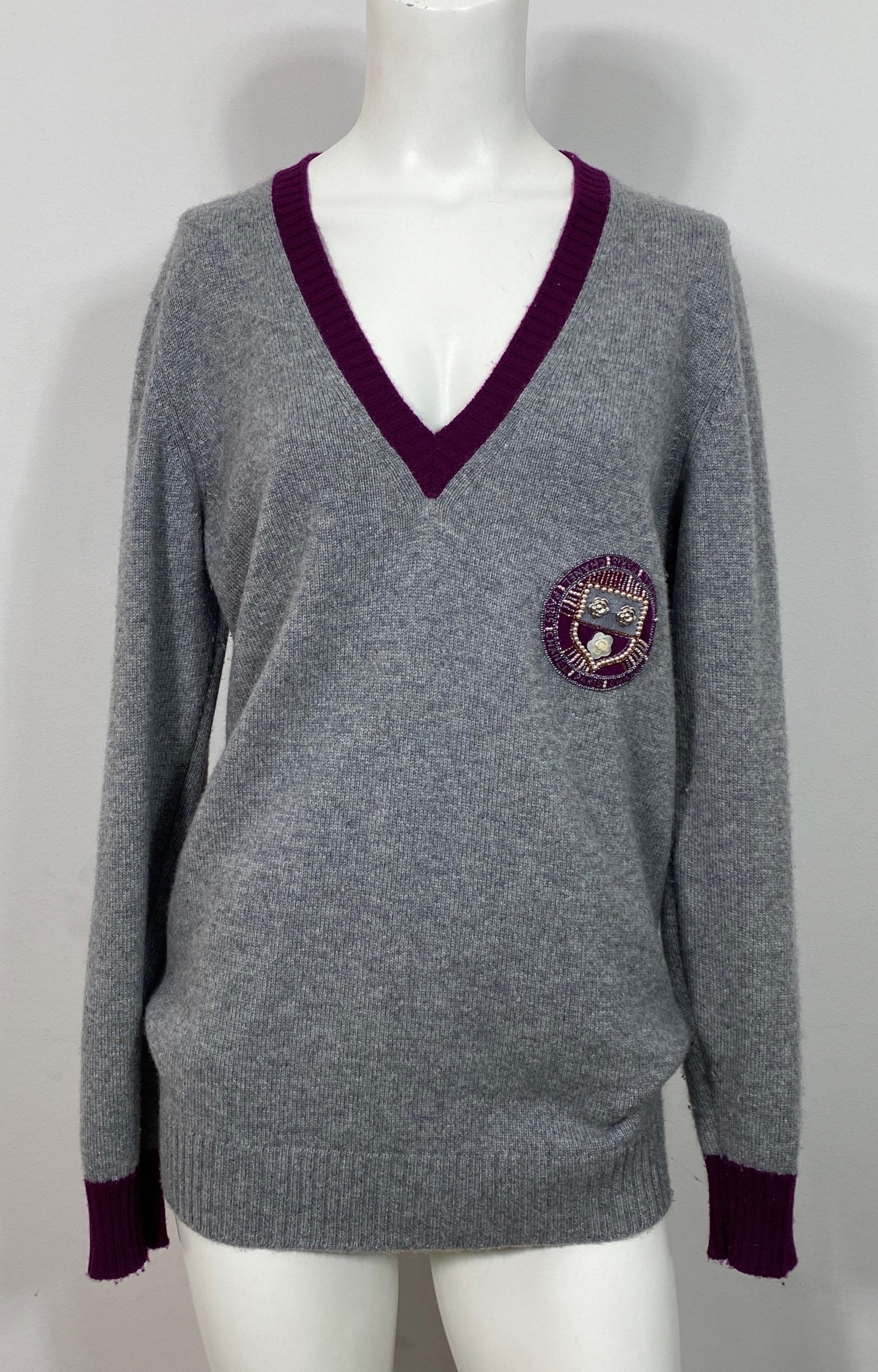 Chanel 2007A Grey and Purple Cashmere Crested V Neck Sweater This vintage 2007A Sweater is labeled a French 46, however if worn as a longer semi oversized piece then it would fit a Medium/Large. Please see measurements for more detail. The Crest is