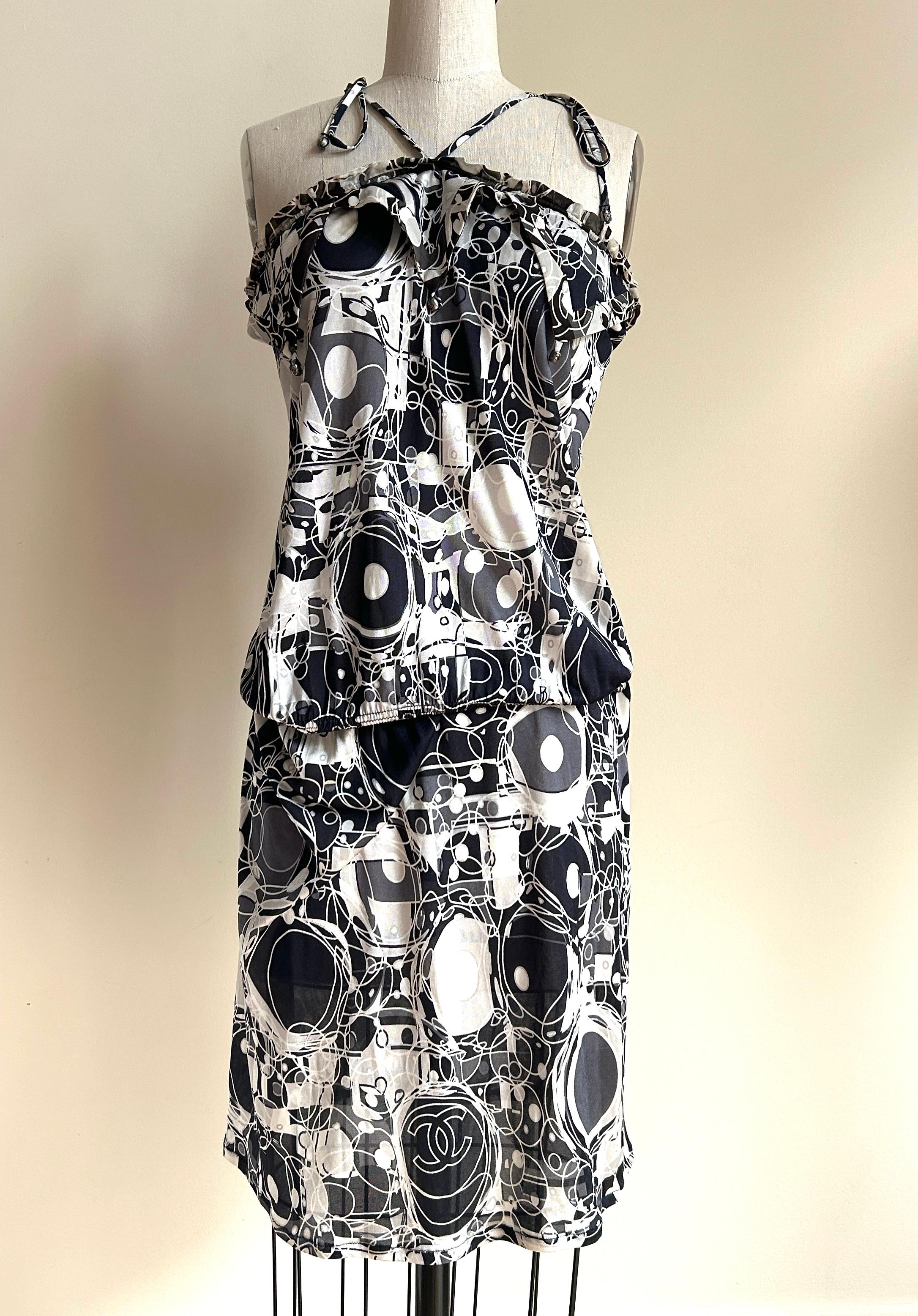 Chanel vintage 2000s black and white geometric logo print sun dress from the from the 2008 collection. Fun triangular detailing at chest with halter ties at neck. Gunmetal tone CC logo print beads adorn the ends of the triangles and ends of the