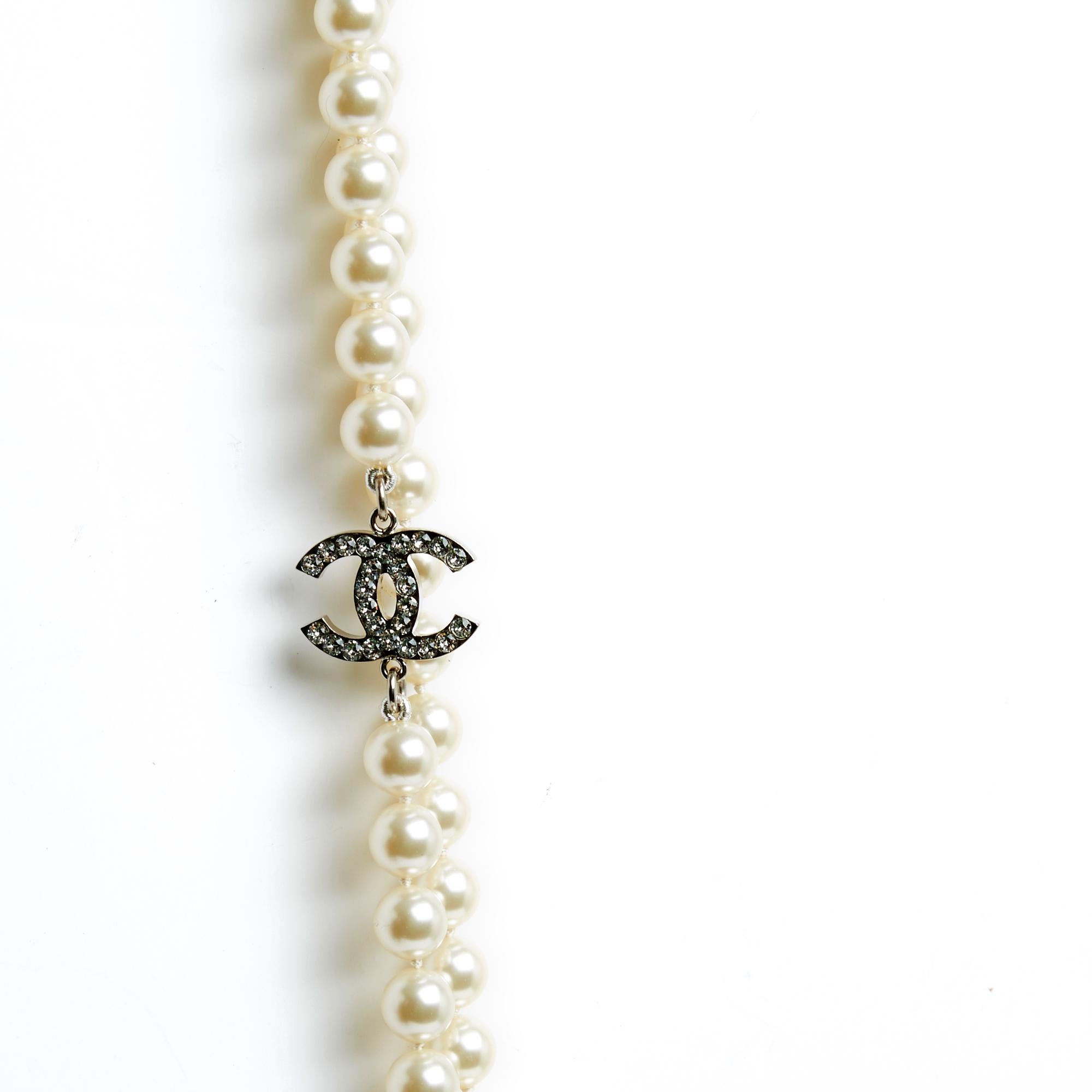 Chanel long necklace dating from 2008 composed of a very long row of fancy pearls interspersed with 5 Chanel CC logos in silver metal inlaid with white rhinestones, closing with a carabiner, logo. Total length of the necklace (closed!) 112 cm,
