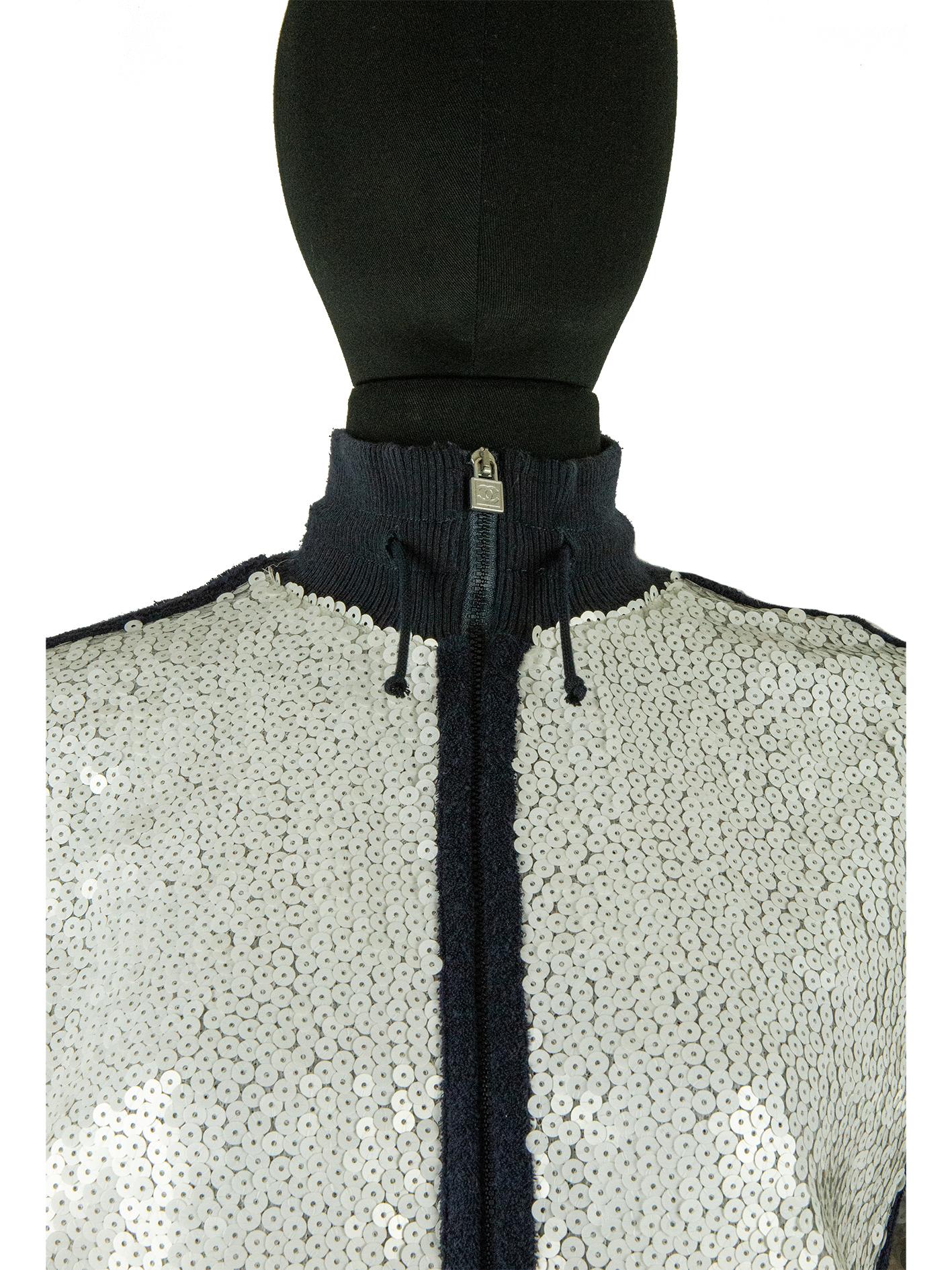 An icy white sequin-covered Chanel jacket from the cruise collection of 2008. This sporty jacket is an all-over covering of sequins in silvery white. With contrasting navy around the elasticated high neck collar, down into the zipper, into the
