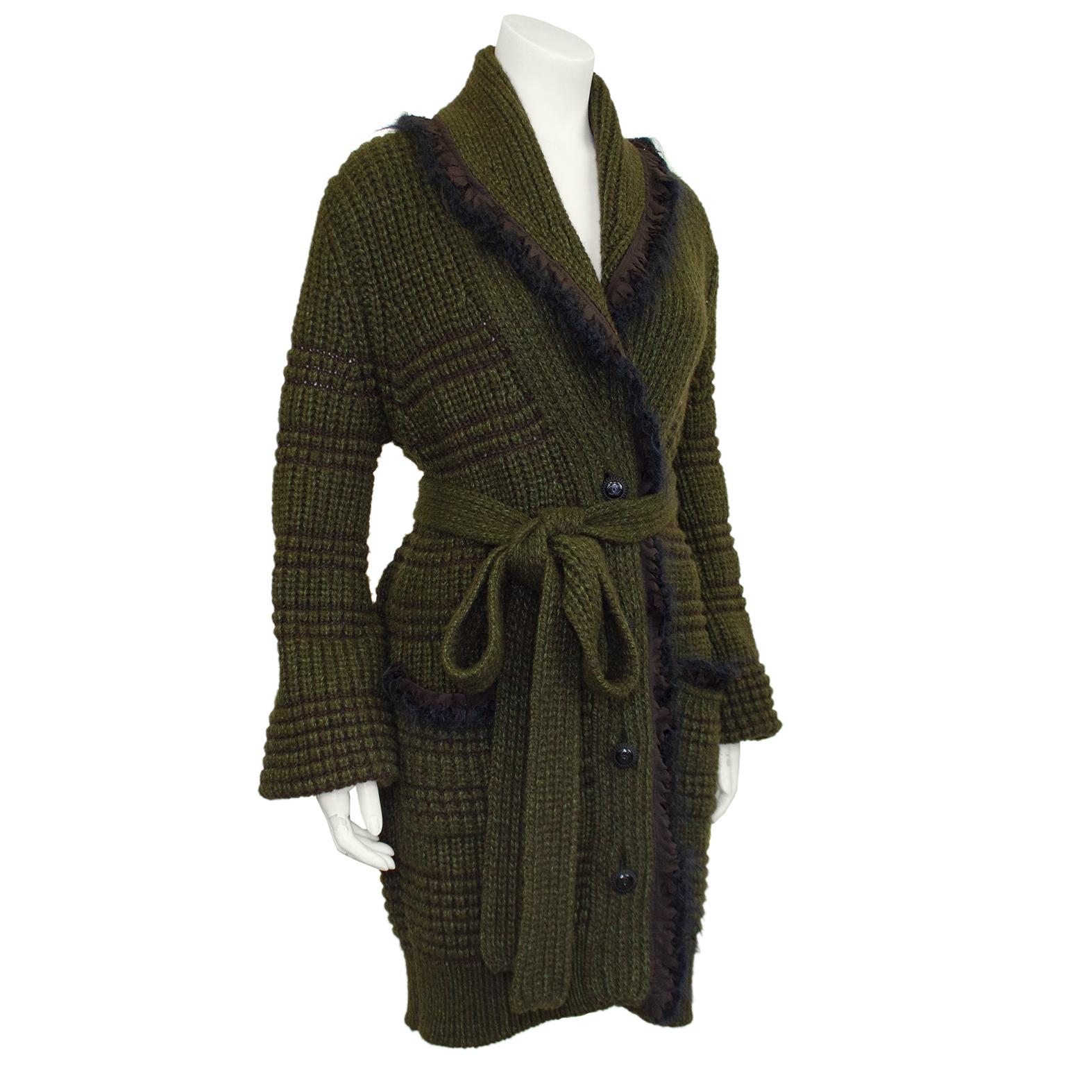 Chanel 2008A autumn collection sweater coat with fringed edge and  shawl collar. Deep olive green and brown knit with CC logo antique silver finished buttons. Self tie belt and two large patch pockets below the hips. Made from 88% yak wool and 12%