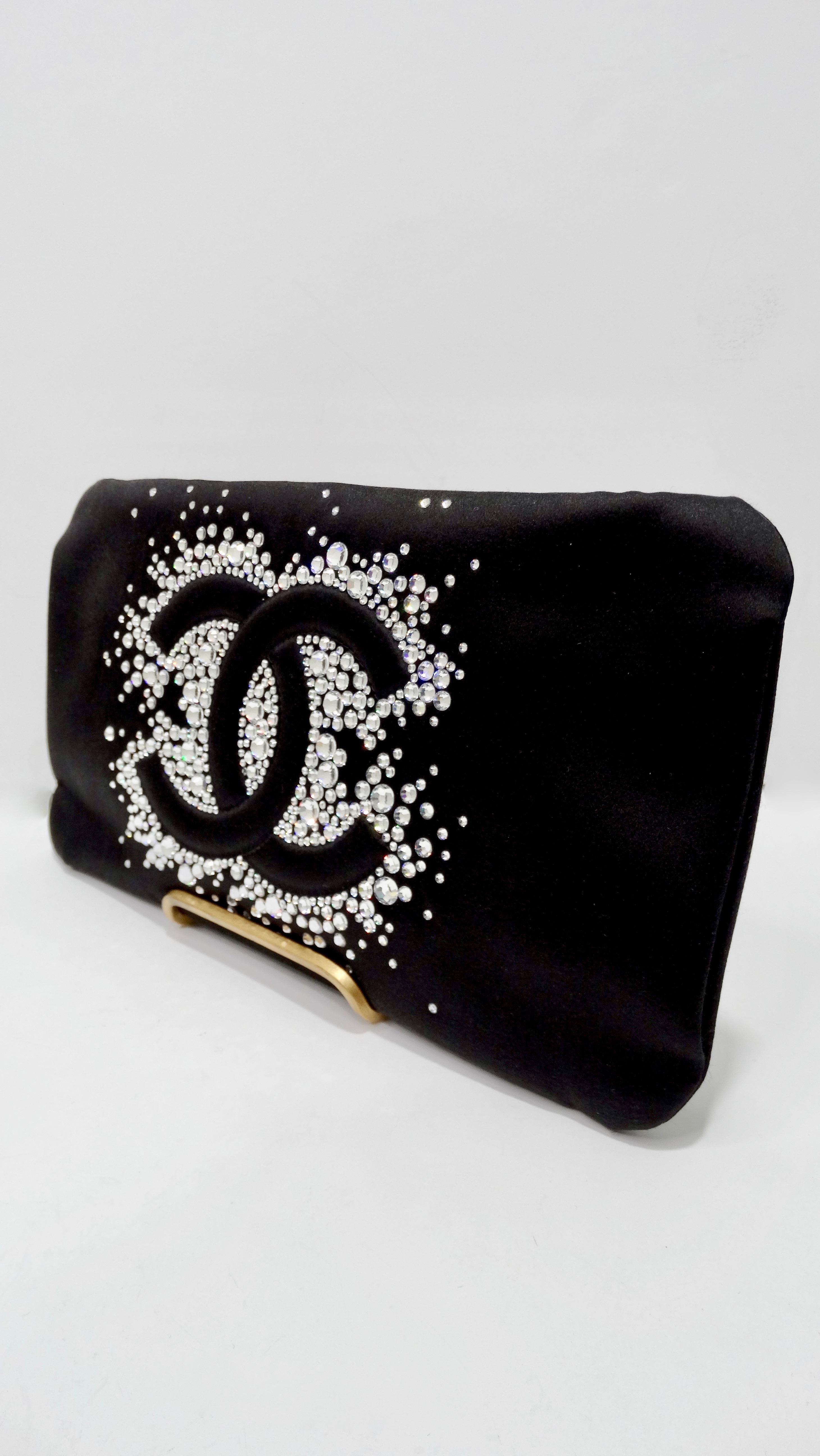 Elevate all your evening looks with this amazing Chanel clutch bag! Circa 2009, this black satin evening clutch features the iconic CC logo surrounded by glittering crystal rhinestones, a top zipper closure, and a single ruthieum chain. Interior is