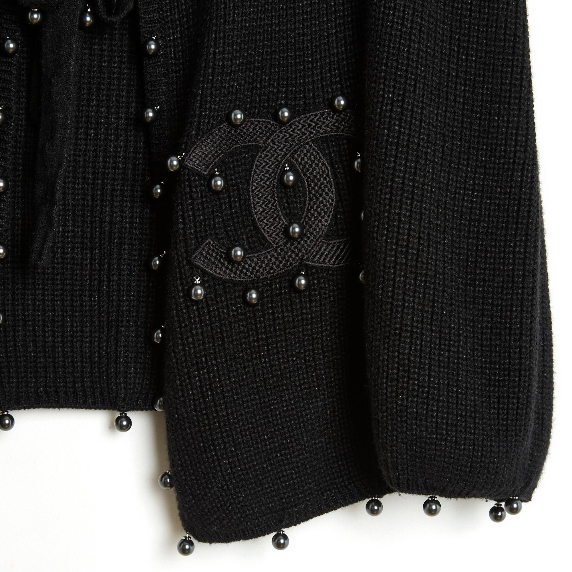 Cardigan Chanel della collezione SS2009 di Karl Lagerfeld in maglia nera di cachemire, seta e lino decorata con perle nere (o grigio scuro) intorno al colletto, alle maniche e al fondo del cardigan, ampio scollo chiuso sul davanti da una lunga