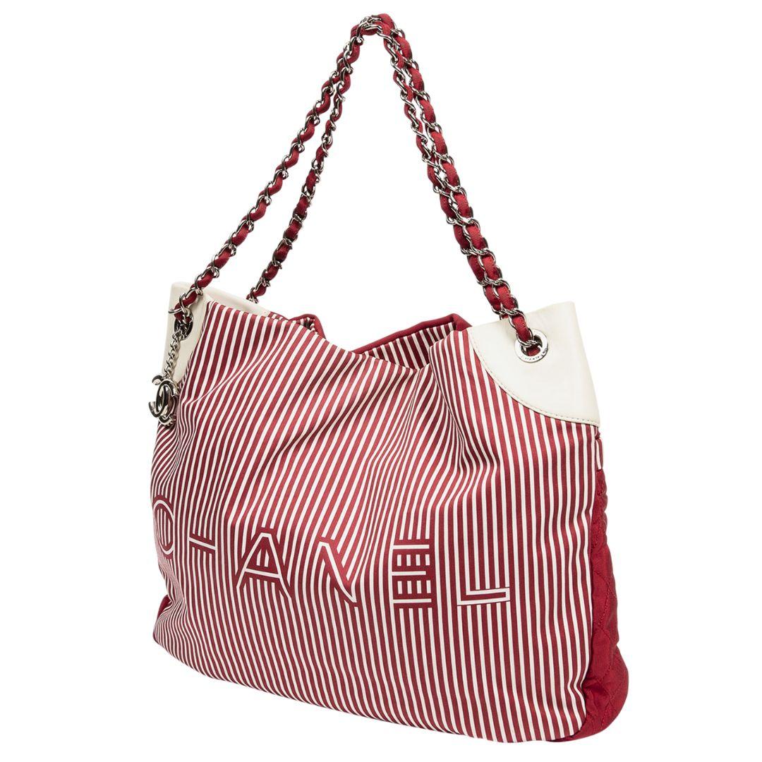 The most perfect summer tote has arrived! The front face is crafted in a red and ivory striped verti canvas with the back of the bag in a solid red canvas with one large snap closure pocket. The silver hardware pairs so well with the red and ivory