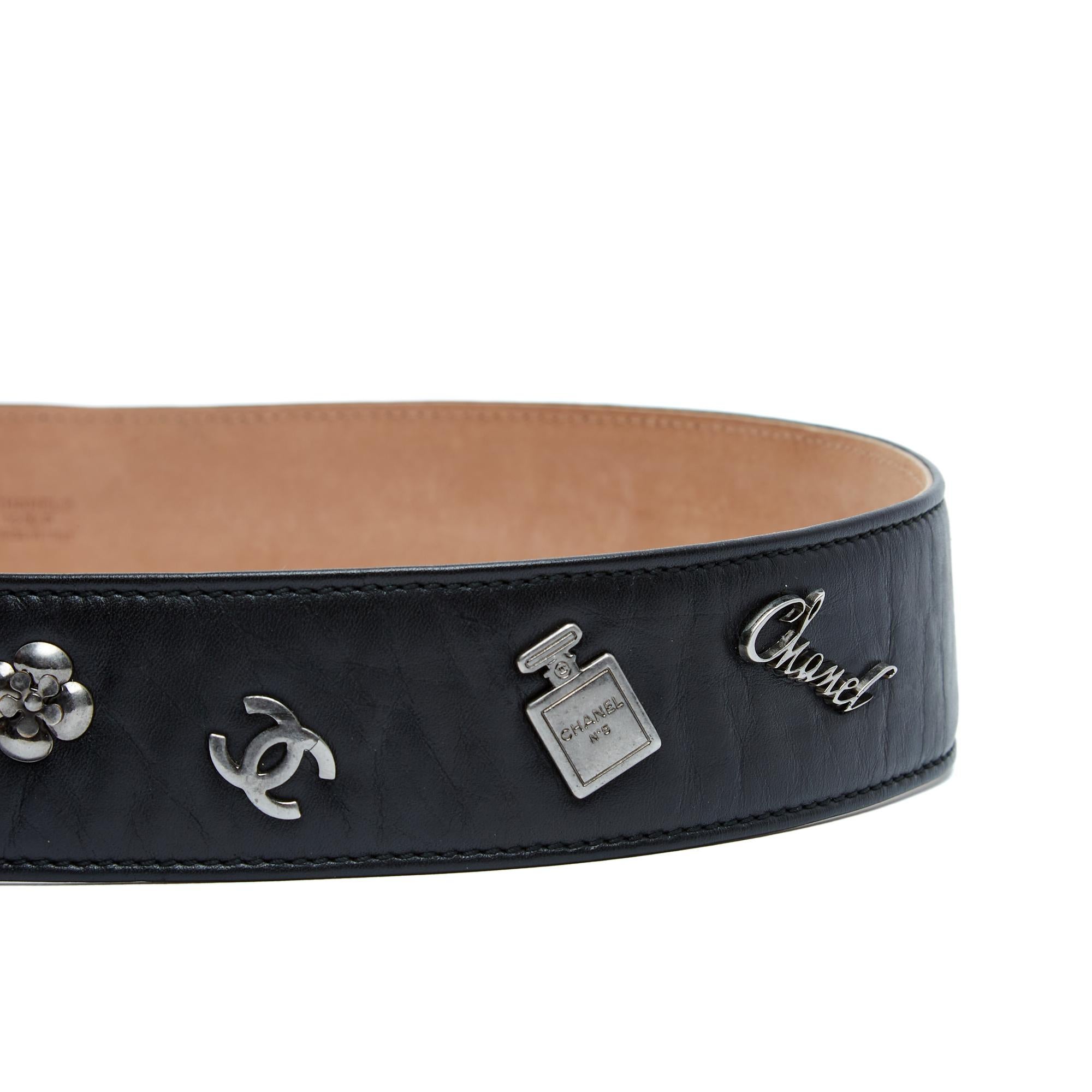 Cintura Chanel della collezione SS2010 in pelle nera decorata con 4 motivi iconici di Chanel (firma Chanel, camelia, logo CC e bottiglia N°5), chiusa da una fibbia con un grande motivo CC su 5 fori. Taglia 90 o US36: lunghezza totale della cintura