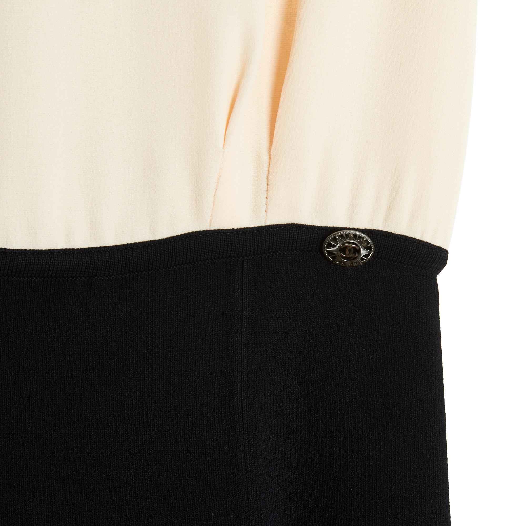 Chanel 2010 dress composed of an ecru silk crepe top, large rounded collar, sleeveless and a skirt, high waist almost empire (below the ribs), in black viscose and elastane knit decorated with a Chanel logo in blackened silver metal. Size 36FR or