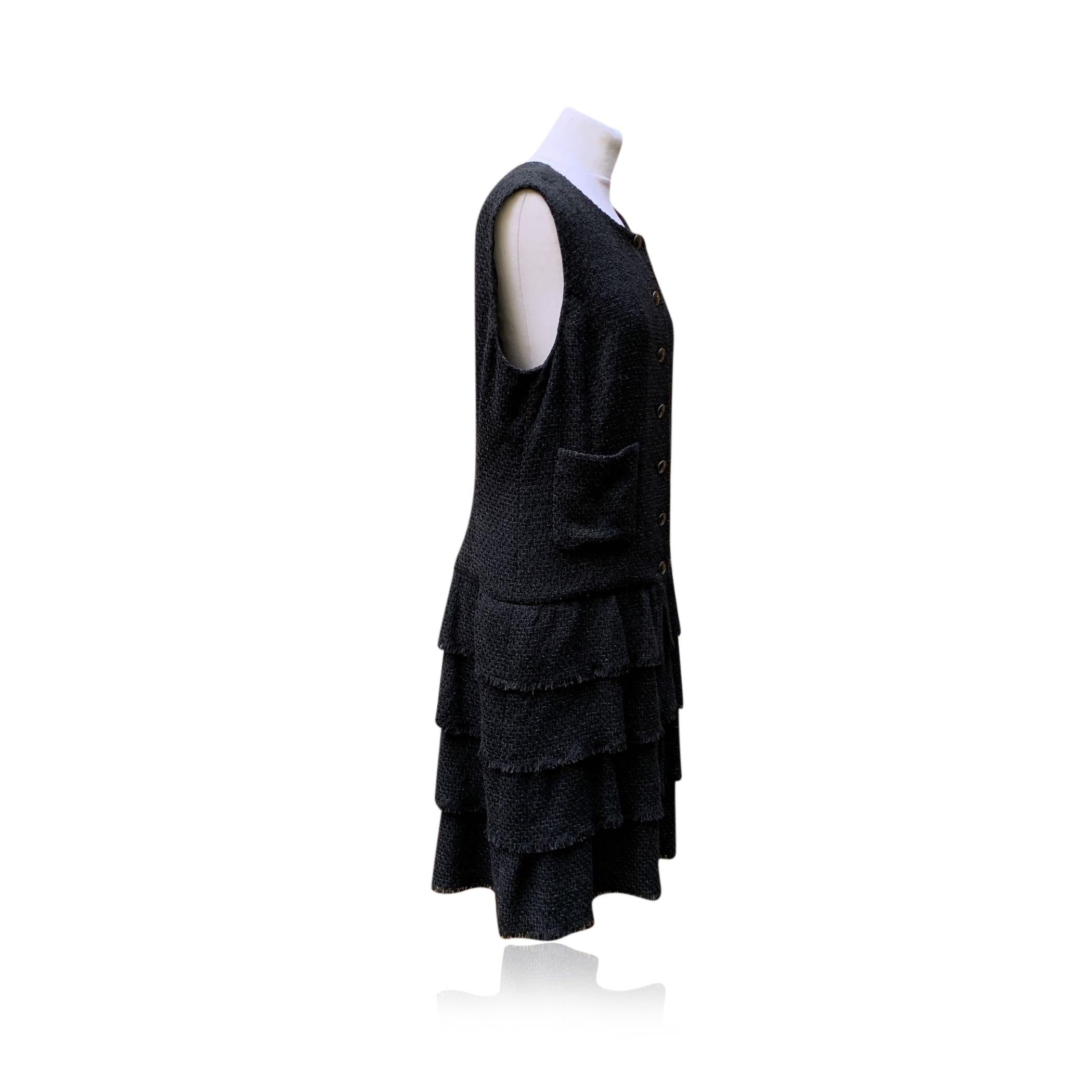 Chanel cotton blend tweed dress from the 2012 spring collection. Sleeveless styling. Front button closure. 2 pockets on the front. Tiered skirt. Composition: 60% cotton, 24% nylon, 16% acrylic. 100% silk lining in black with Camellia pattern. Size:
