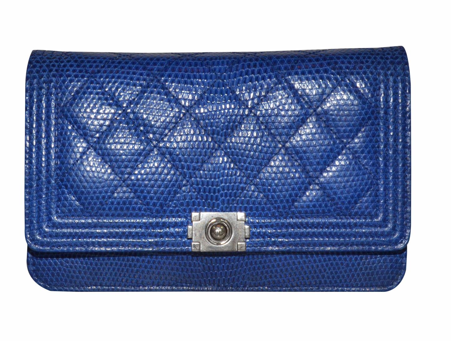 Chanel wallet on a chain is featured in blue lizard skin with a diamond quilt and gunmetal hardware. Bag has a snap closure and is fully lined. Interior offers a slip pocket, 2 zippered pockets, and an open compartment with card slots. Dustbag is
