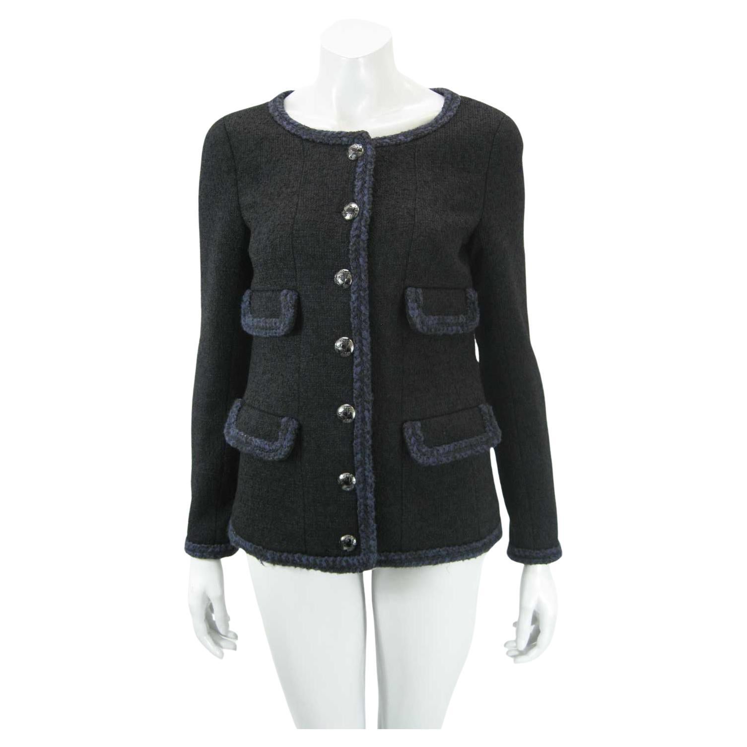 Clásica y rara chaqueta Chanel negra de mezcla de lana.

De la colección AW 2013. 

Ribete trenzado resaltado con tonos azul oscuro.

Cuatro bolsillos de imitación.

Botones en relieve con CC y gráfico del mundo.

Forrado de seda.

Tagged talla