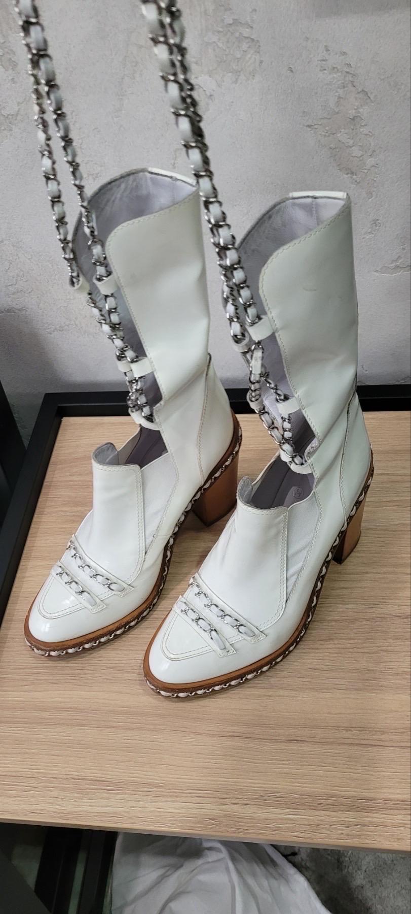 Chanel 2013 White Patent Leather Chain Obsession Heeled Calf Boot. 
Almond toe. 
Pull-on. 
Tonal stitching. 
Strap with buckle closures. 

Sz.40


Very good condition.  Signs of wear seen on pics.
No box. No dust bag