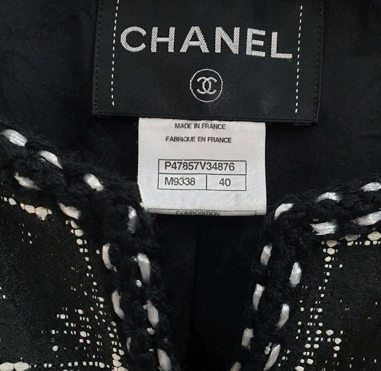 A Chanel black and white double breasted jacket from the Spring 2014 collection. The jacket has two front pockets, eight basket weave CC logo buttons down the center, four matching buttons on each sleeve and black and silver knitted trim detailing.