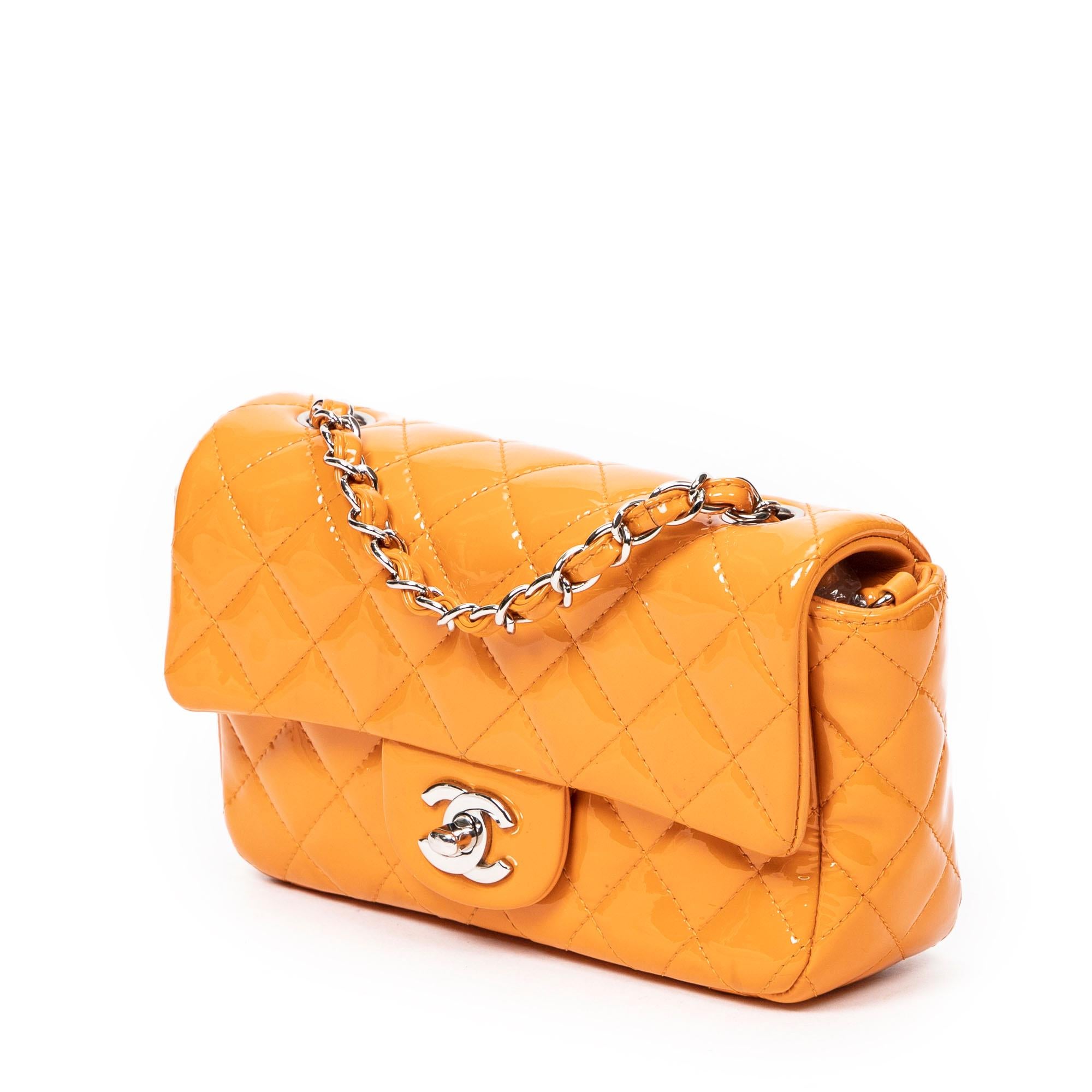 Chanel's 2014 Mini Single Flap Bag in vibrant orange quilted patent leather features a signature silver CC turnlock and a luxurious leather interior complete with pockets.

SPECIFICS
• Length: 7.5