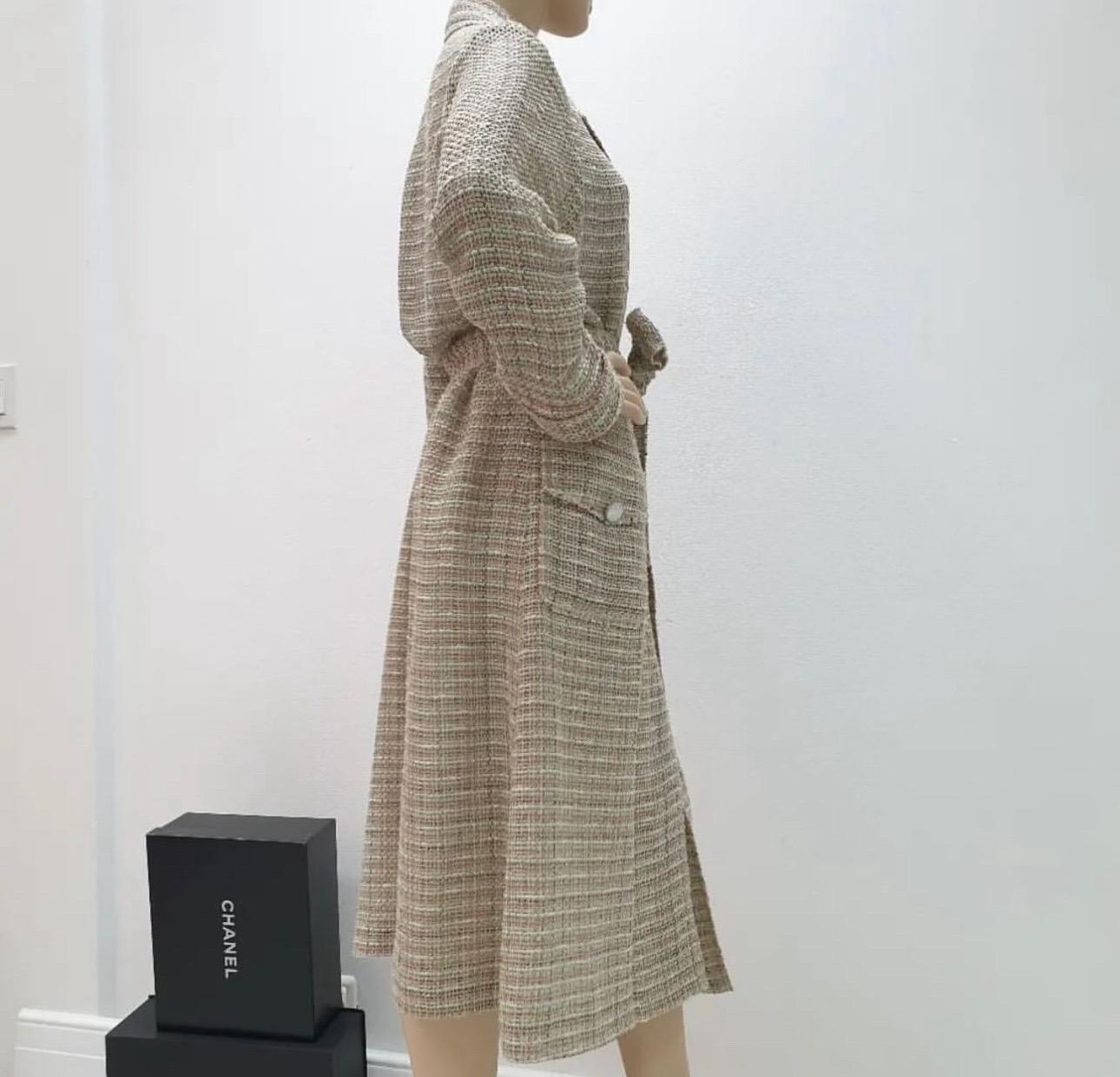 

Chanel tweed coat in beige, ivory, green and coral cotton (45%), linen (27%), nylon (14%)  and acrylic (14%). Features two flap pockets with logo engraved metal buttons. Closes with a matching belt and is lined in cotton (75%) and silk (25%) with