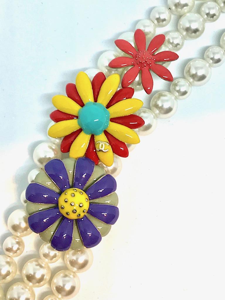 From the Chanel Spring Summer collection of 2017. The bracelet is three strands of pearls and enamel flowers. The faux pearls alternate between 6 and 8 mm in size. The flowers are bright color enamel on gold. The largest central flower has the