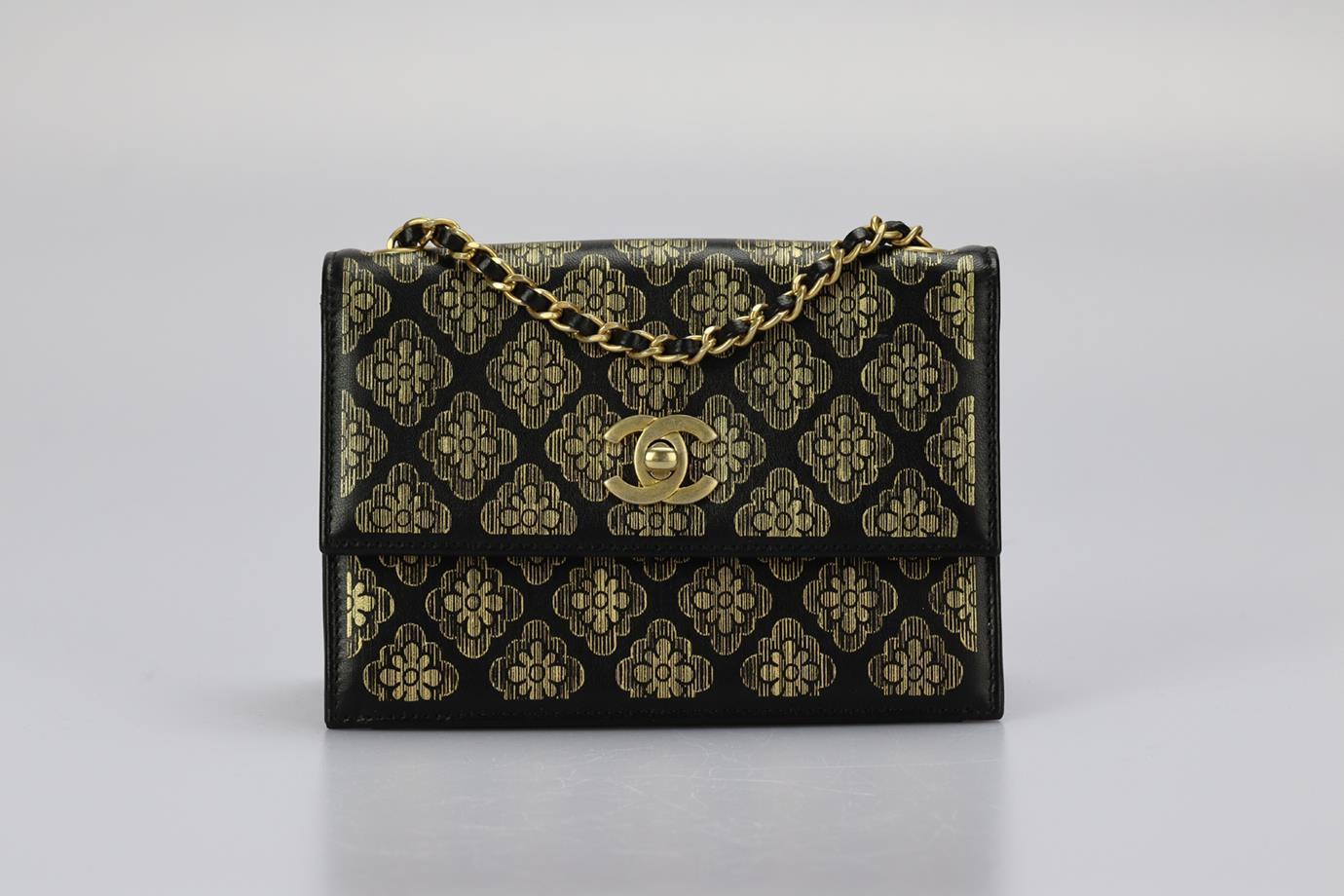 Bolso de hombro de piel con estampado floral Chanel 2017. Negro y dorado. Cierre giratorio 0 Delantero. Viene con - bolsa guardapolvo y tarjeta de autenticidad. Altura: 4,5 pulg. Anchura: 6,8 pulg. Profundidad: 2,5 pulg. Caída de la correa: 23,8