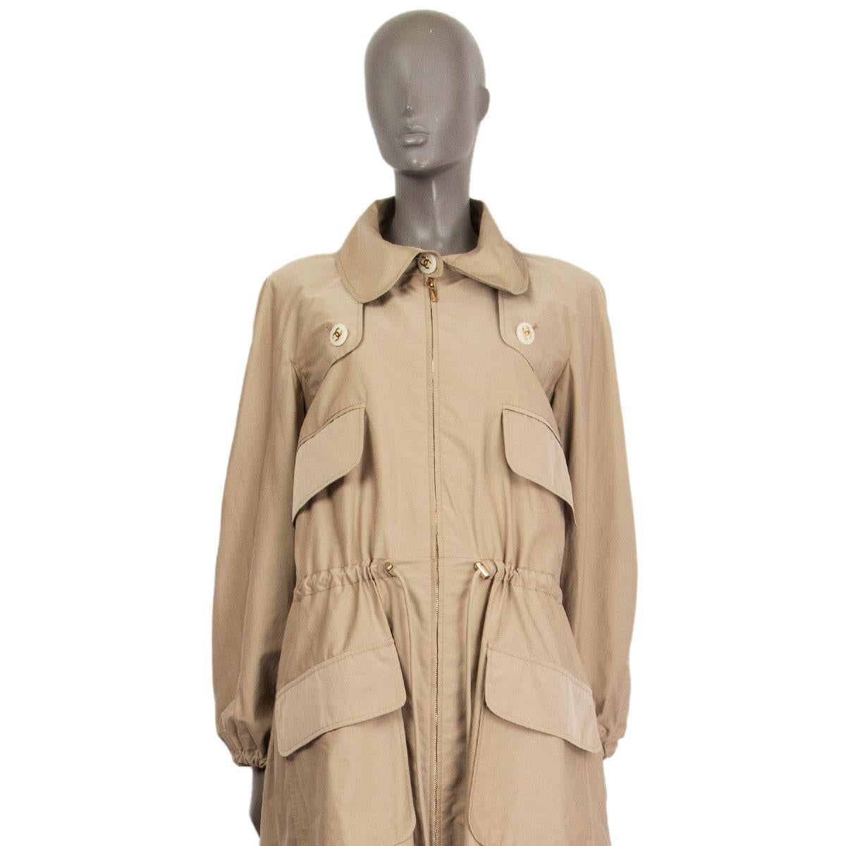100% authentic Chanel Pre-Fall 2018 collection drawstring trench coat in beige cotton (82%) and silk (18%) with logo embossed buttoned storm flap at the front and at the back, four flap pockets at the front and drawstring at the sleeve-hems. Closes