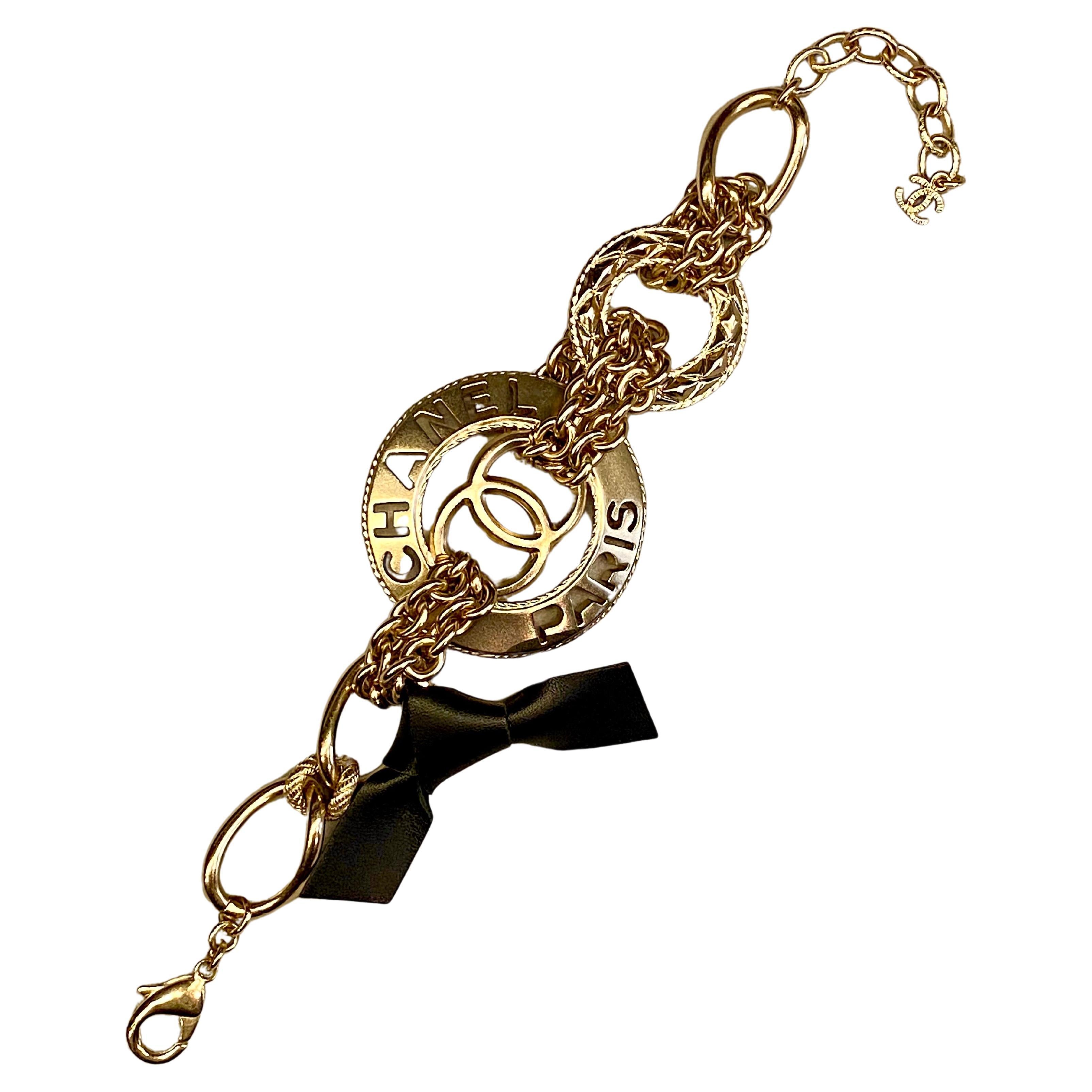 Bracelet à maillons en chaîne à finition or satiné léger de Chanel, issu de la collection automne-hiver 2018. Le grand disque mesure 1,8 pouce et présente une découpe du logo CC emblématique, du nom Chanel et de Paris. D'un côté, un anneau décoratif