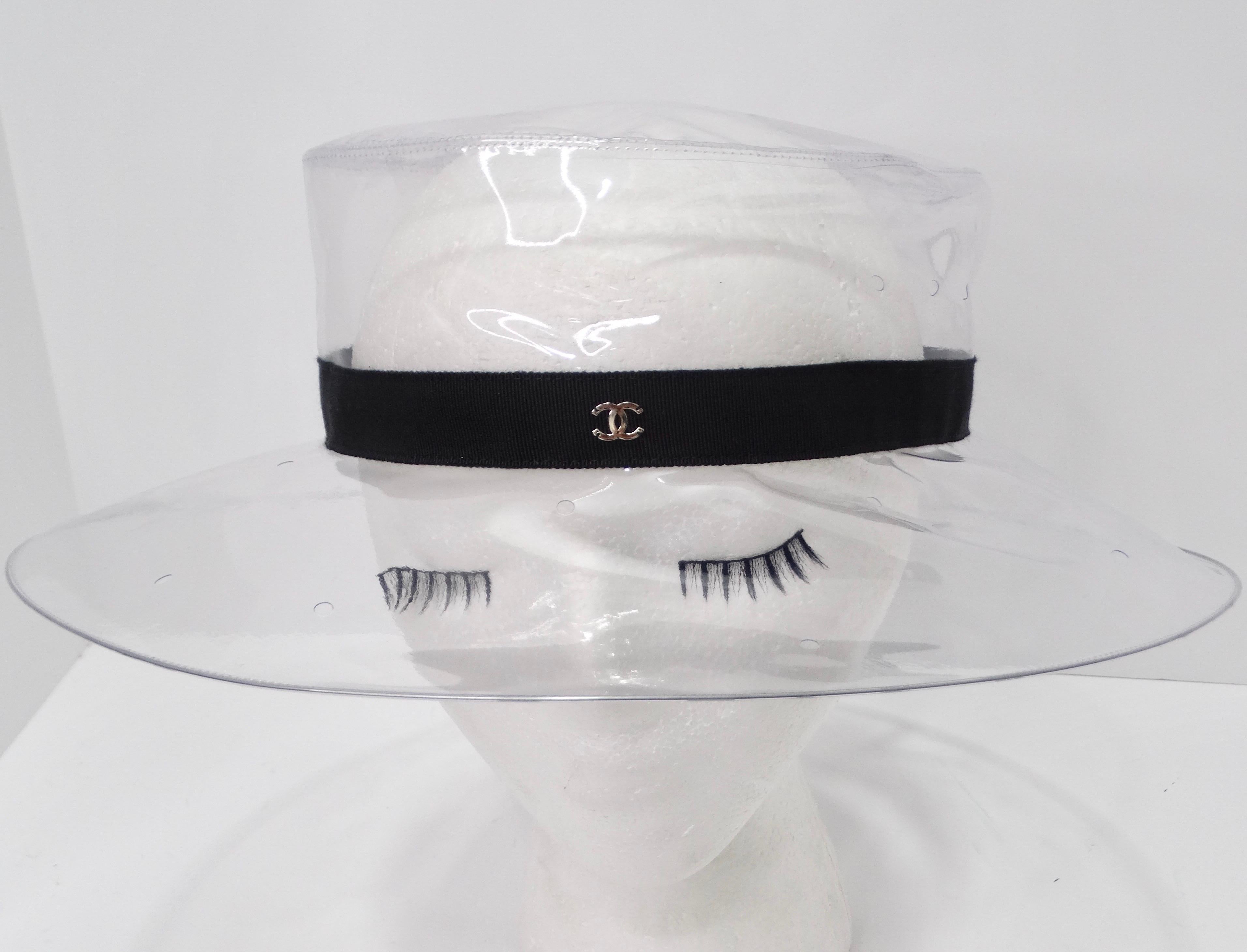 Step into the realm of high fashion with this Chanel 2018 clear PVC sun hat, a must-have accessory for the style-conscious. This exquisite sun hat boasts a black ribbon elegantly wrapped around its base, adding a touch of sophistication to its