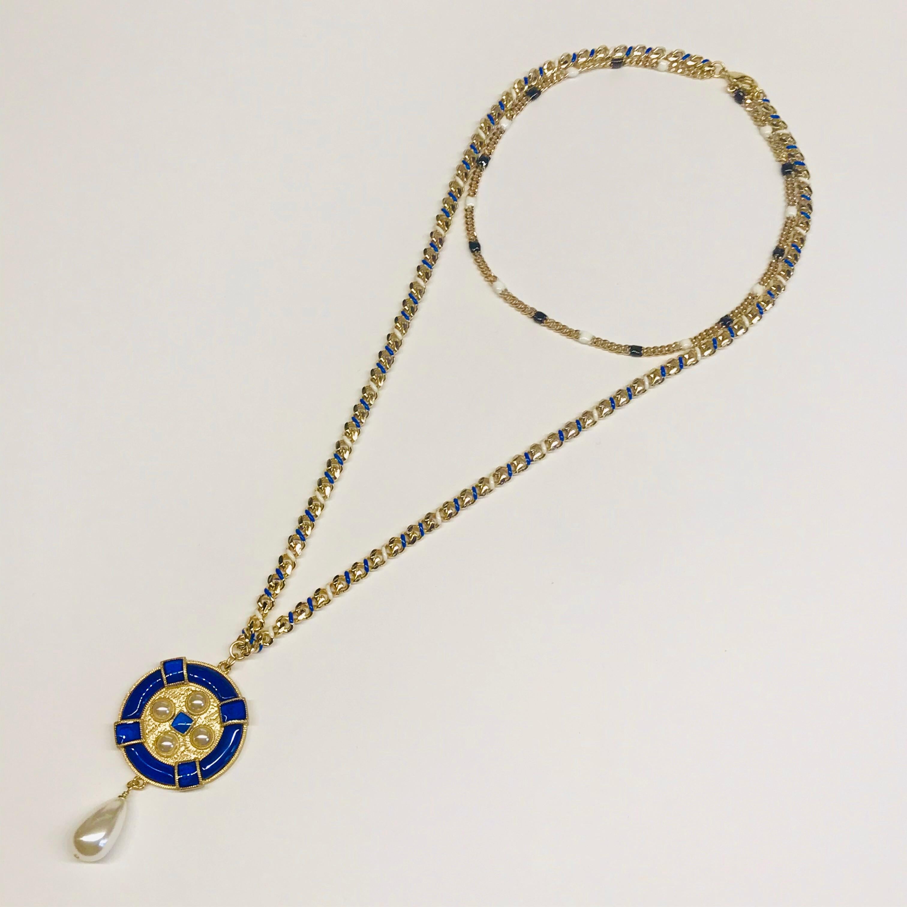 A fabulous Chanel 2019 cruise collection gold tone with white and blue enamel accents double strand pendant necklace. The disk pendant is 1.5” in diameter. The total height of the pendant including the faux pear pearl is 2.5.” The shorter curb link