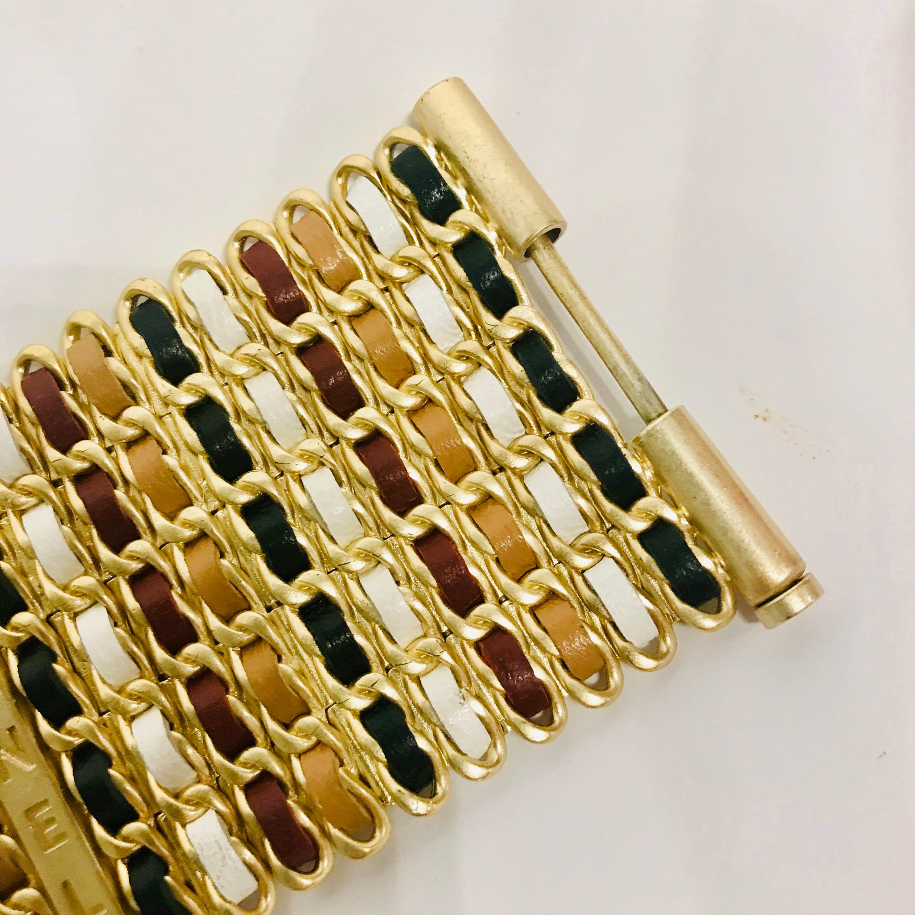 A beautiful wide bracelet from Chanel 2019 cruise collection. Iconic use of leather strips in black, camel and burgundy colors woven in the gold tone metal chain style links. Two long spacer bars inscribed CHANEL to give contrast to the leather work