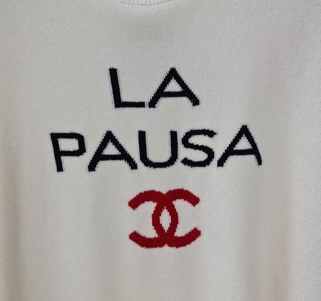 Look 2 vom Laufsteg der Cruise 2019. Elfenbeinfarbener, schwarzer und roter Chanel Pullover aus leichtem Kaschmir mit Rundhalsausschnitt, langen Ärmeln, durchgehendem Rippstrickbesatz und ineinandergreifendem CC 'La Pausa' Intarsienmuster auf der