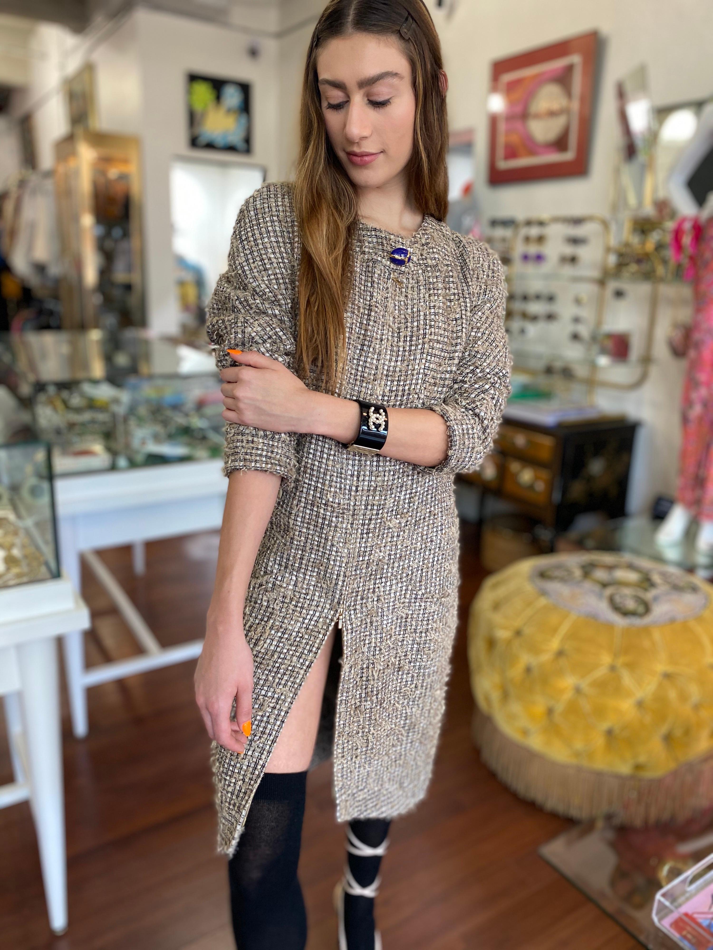 Calling all Chanel lovers! Circa 2019 from their pre-fall collection, this long sleeve dress is crafted from shimmery silver/black/tan tweed and features a rounded neckline with a large blue and gold scarab beetle button embossed with a mini CC.