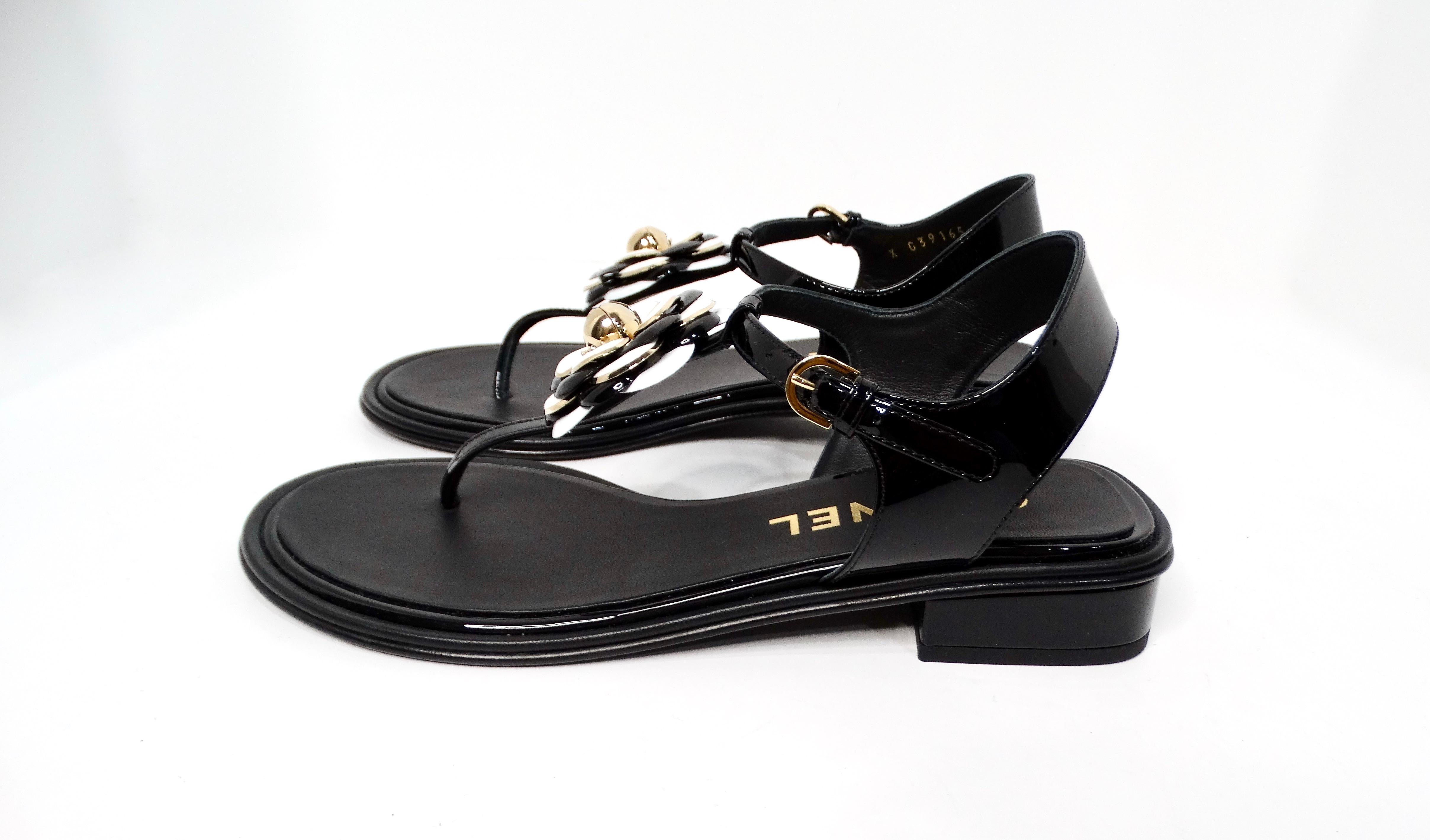 Step into sophistication with the Chanel 2022 Camellia Patent Leather Sandals, an exquisite marriage of elegance and contemporary flair. These black leather sandals feature sleek patent leather detailing, showcasing the minimalist yet striking form