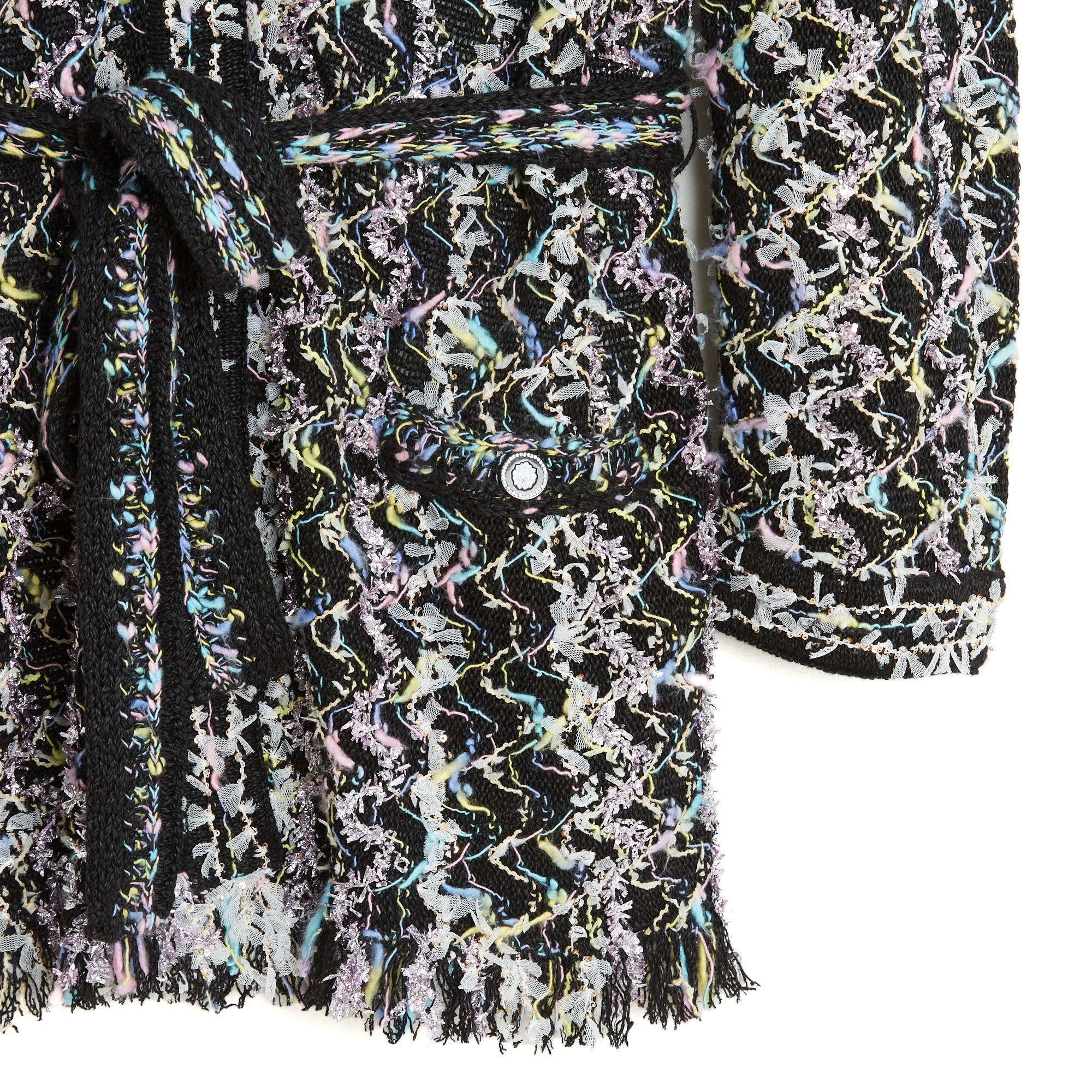 Cardigan Chanel della collezione SS2022 a mo' di giacca, in maglia di tweed di viscosa nera mescolata con fili d'argento, bianchi, rosa e blu in un motivo trapuntato, profondo scollo a V sul davanti chiuso da 3 bottoni con l'immagine di Coco Chanel,