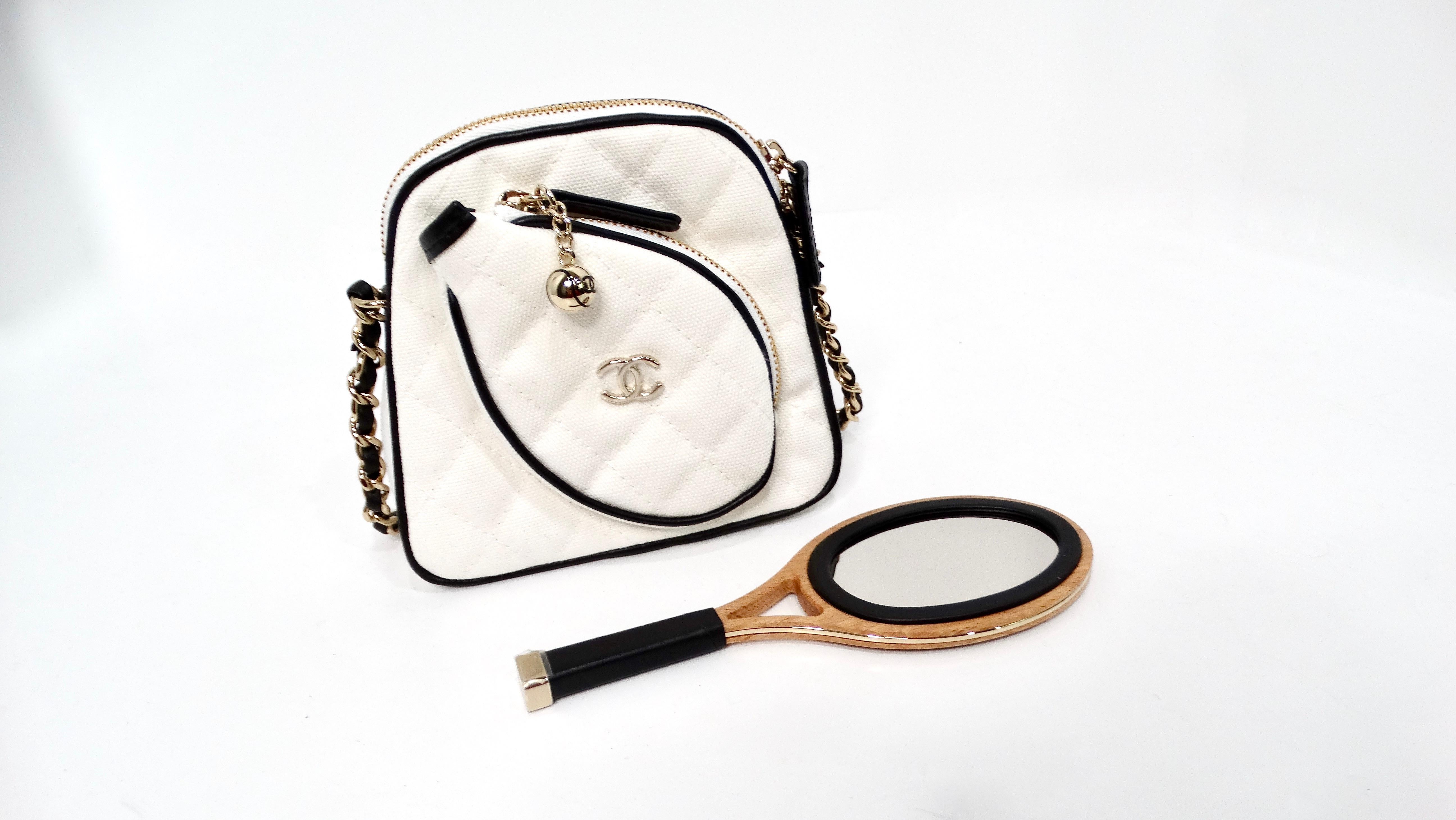 The Chanel 2023 Coco Masters White Mini Tennis Cloth Crossbody Bag is a whimsical yet refined statement piece that captures the essence of sporty luxury. Crafted from high-quality cloth, this unique bag flaunts a playful design featuring a mini