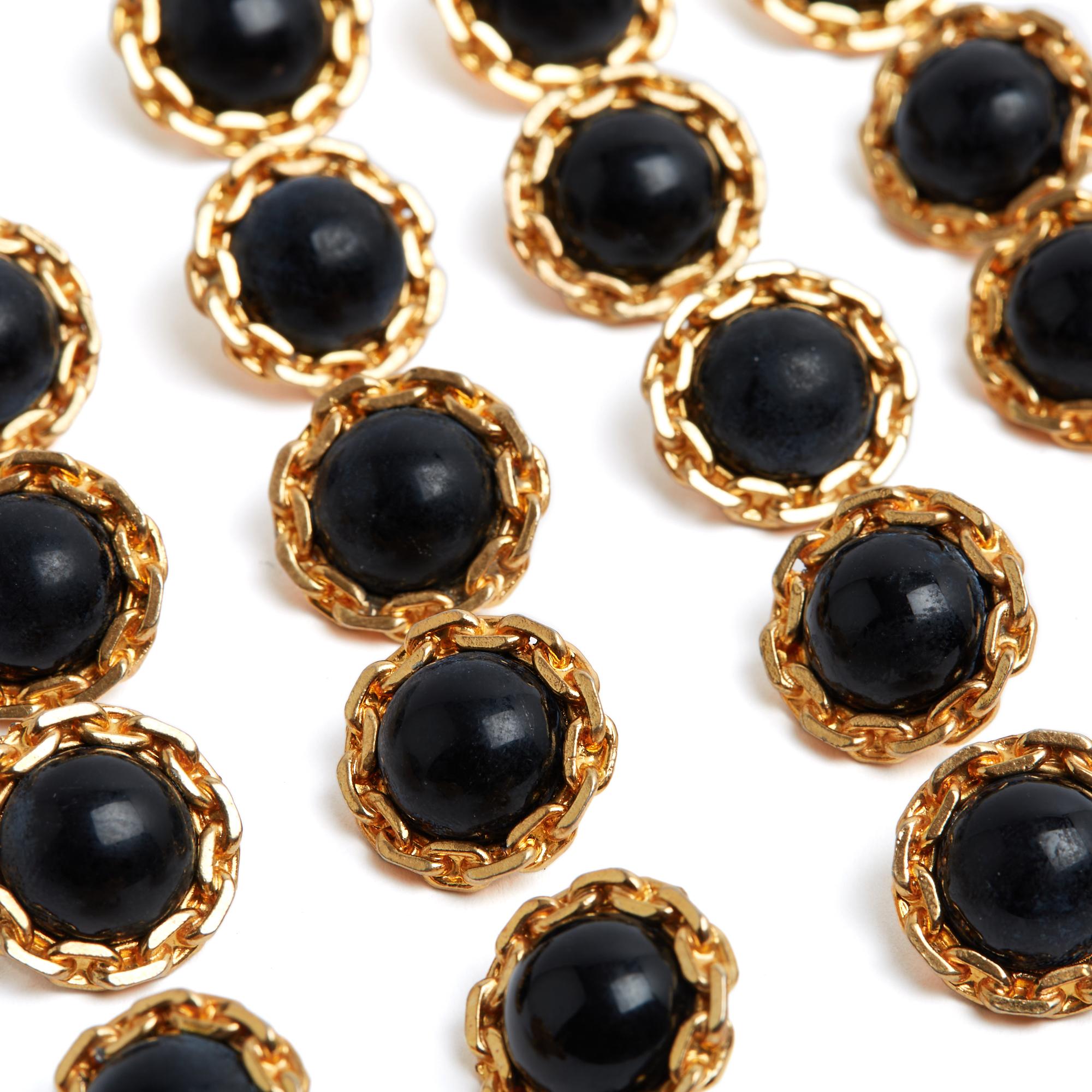 Chanel buttons circa 1980, diameter 1.9 cm in gold-plated metal with a chain motif surrounding a half black glass pearl, quantity 21, height of the button (including the foot) 1.3 cm. The buttons are signed, in very good condition.