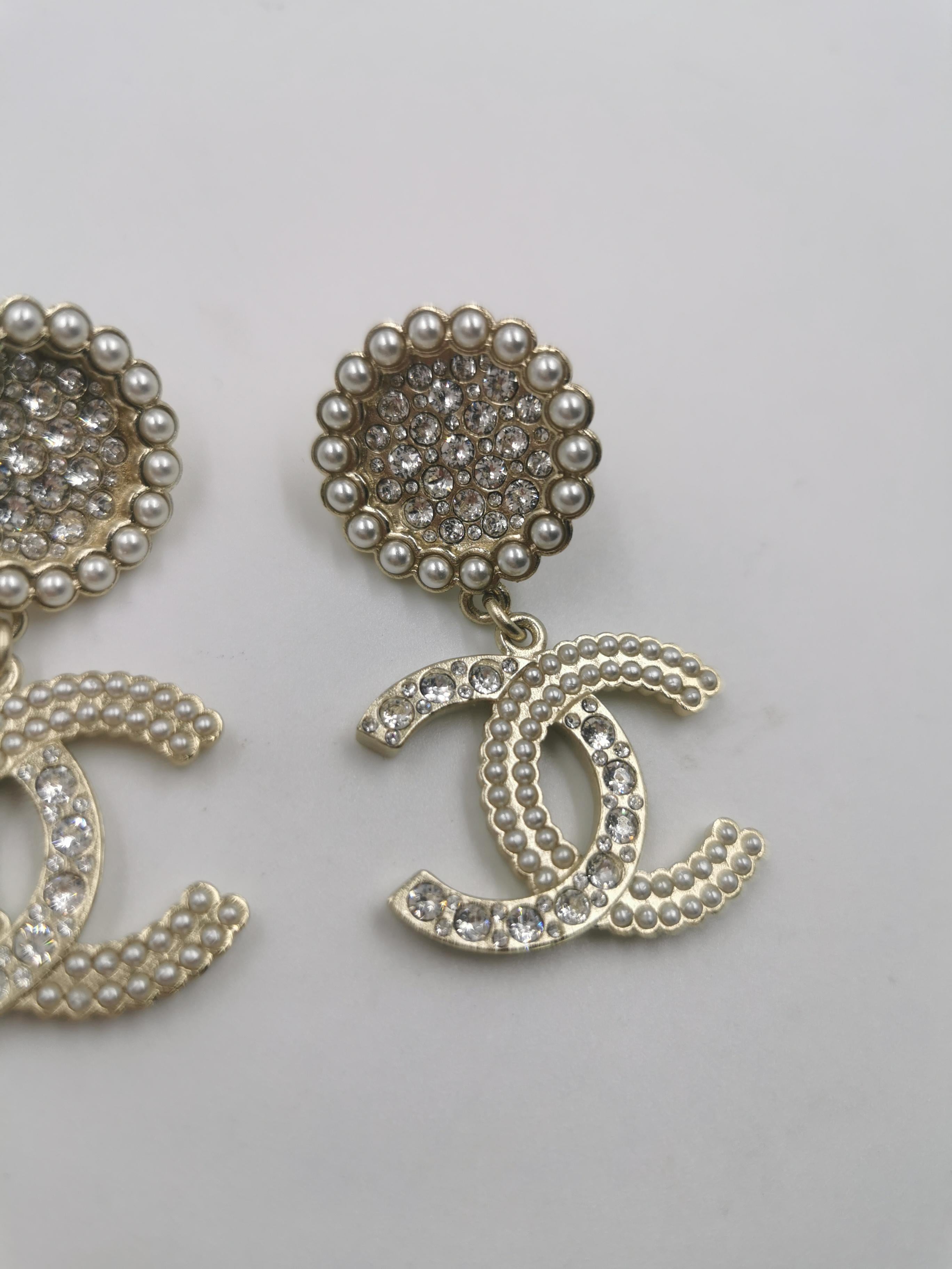 Introducing the captivating Chanel 21 Runway CC Light Gold LARGE Massive Rhinestone Logo Dangling Earrings. These earrings are a true testament to the timeless elegance and iconic design that Chanel is celebrated for, making them a must-have
