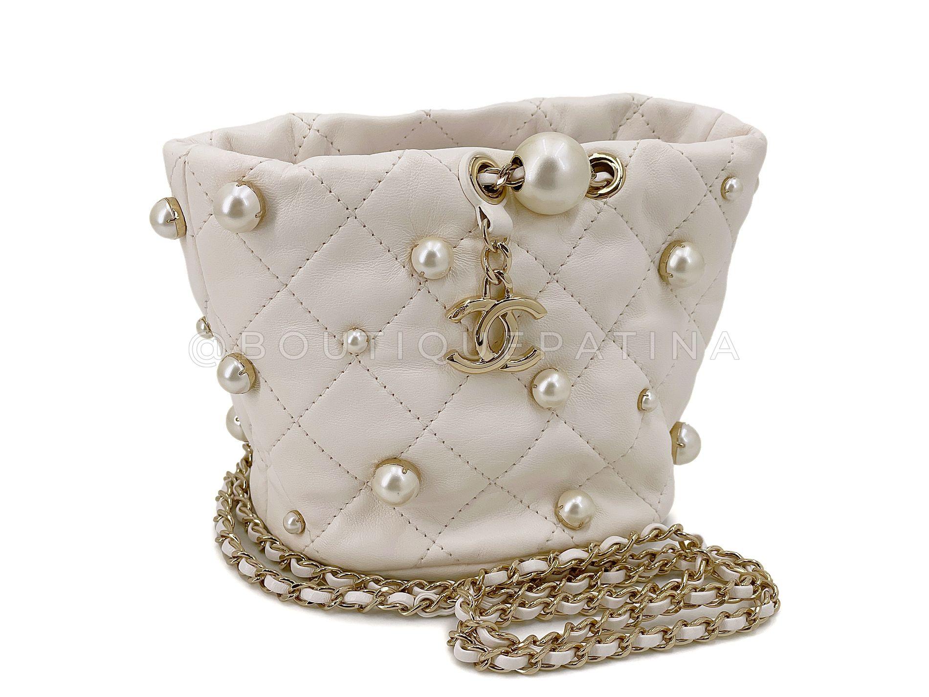Store item: 67973
Chanel 21S White Cream About Pearls Bucket Bag Mini  is a pillowy soft miniature bucket bag adorned with gold-pronged faux pearls and dangling CC charm hardware, with a woven crossbody strap. 

Perfect for evening or everyday, with