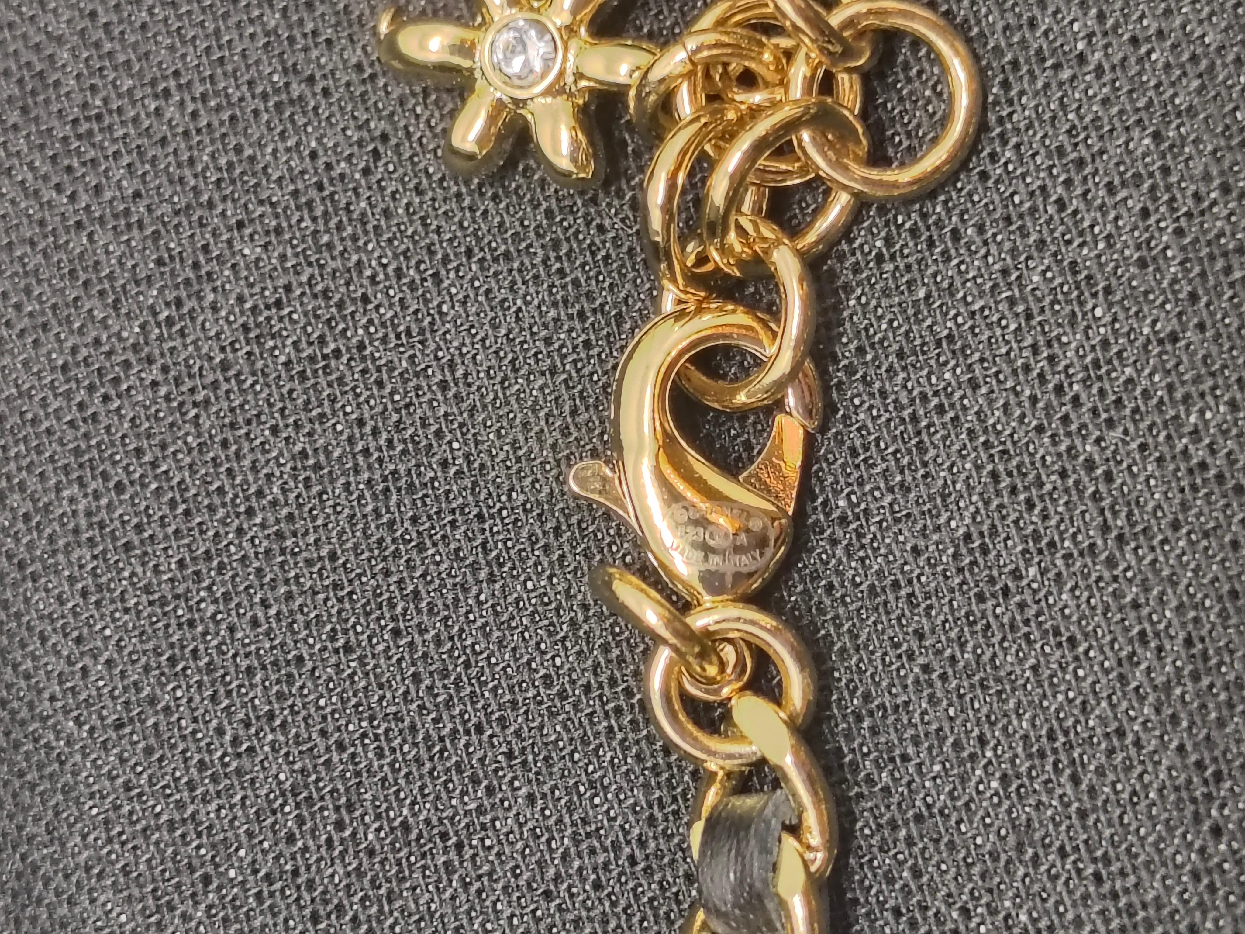 Questa collana dell'ambita Chanel 23A Collection unisce l'eleganza senza tempo della Maison con un tocco moderno. Realizzato con una catena dorata intrecciata con pelle nera, il pezzo è centrato da un ciondolo con logo CC abbellito da cristalli
