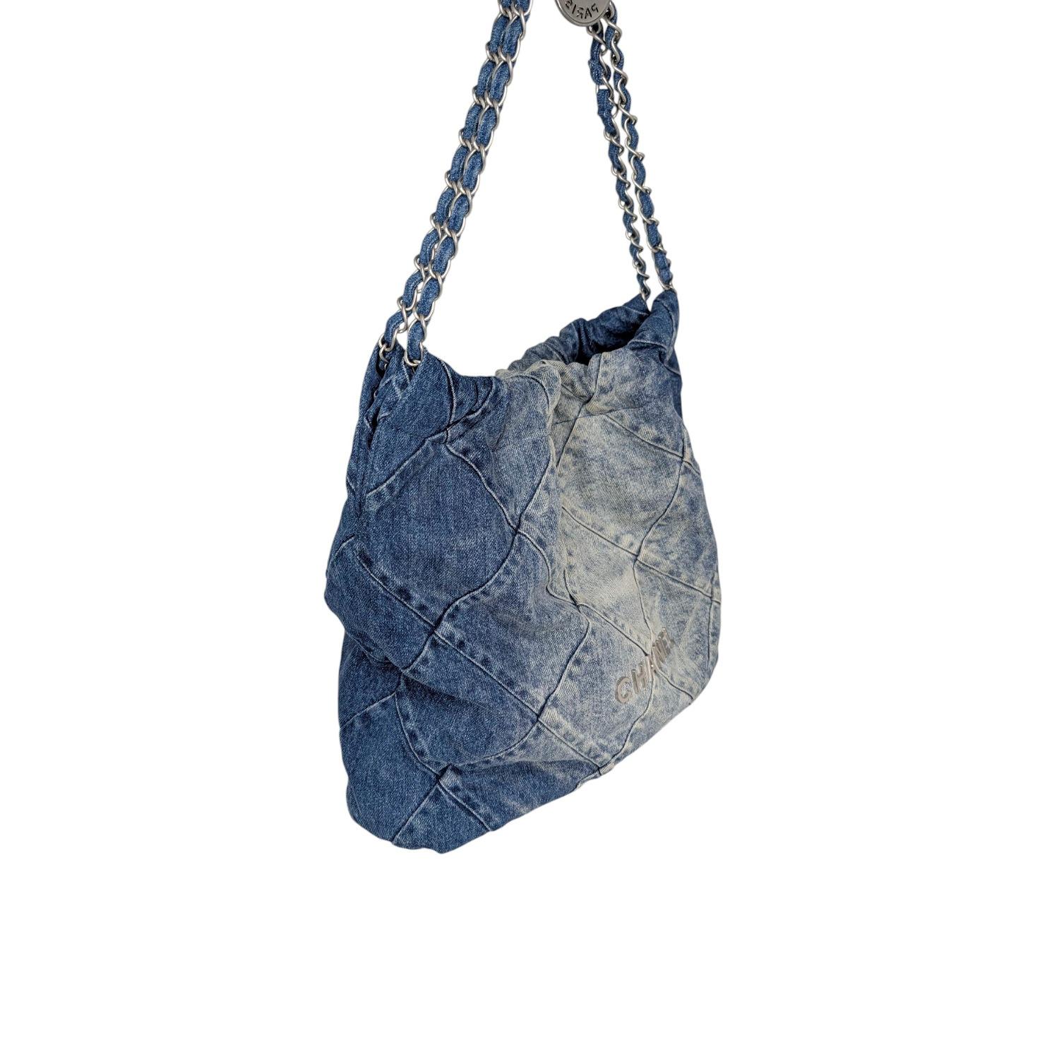 Crafted in Italy, this Chanel 22 Hobo bag is a timeless piece that blends everyday style with signature luxury. The bag's exterior is a rich blue denim, featuring a quilted diamond-stitched pattern and a subtle silver metal Chanel logo. Its magnetic