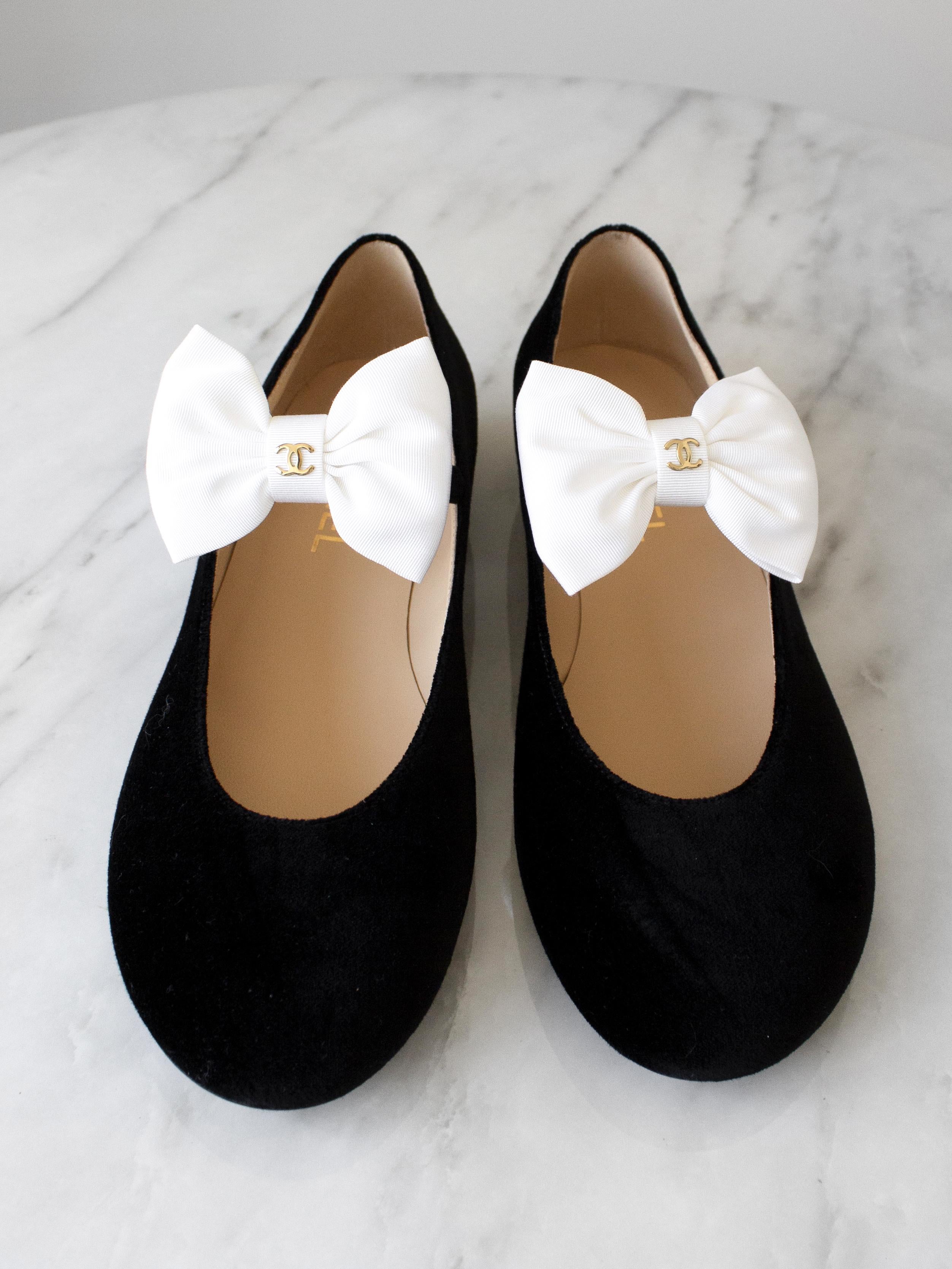 The most wanted black velvet mary jane shoes from Chanel Metiers D'Art 2024 collection. These lovely flats have detachable white bows embellished with signature CC logo and multicolored Gripoix buckles. Size 39. New with box, dust bags and care