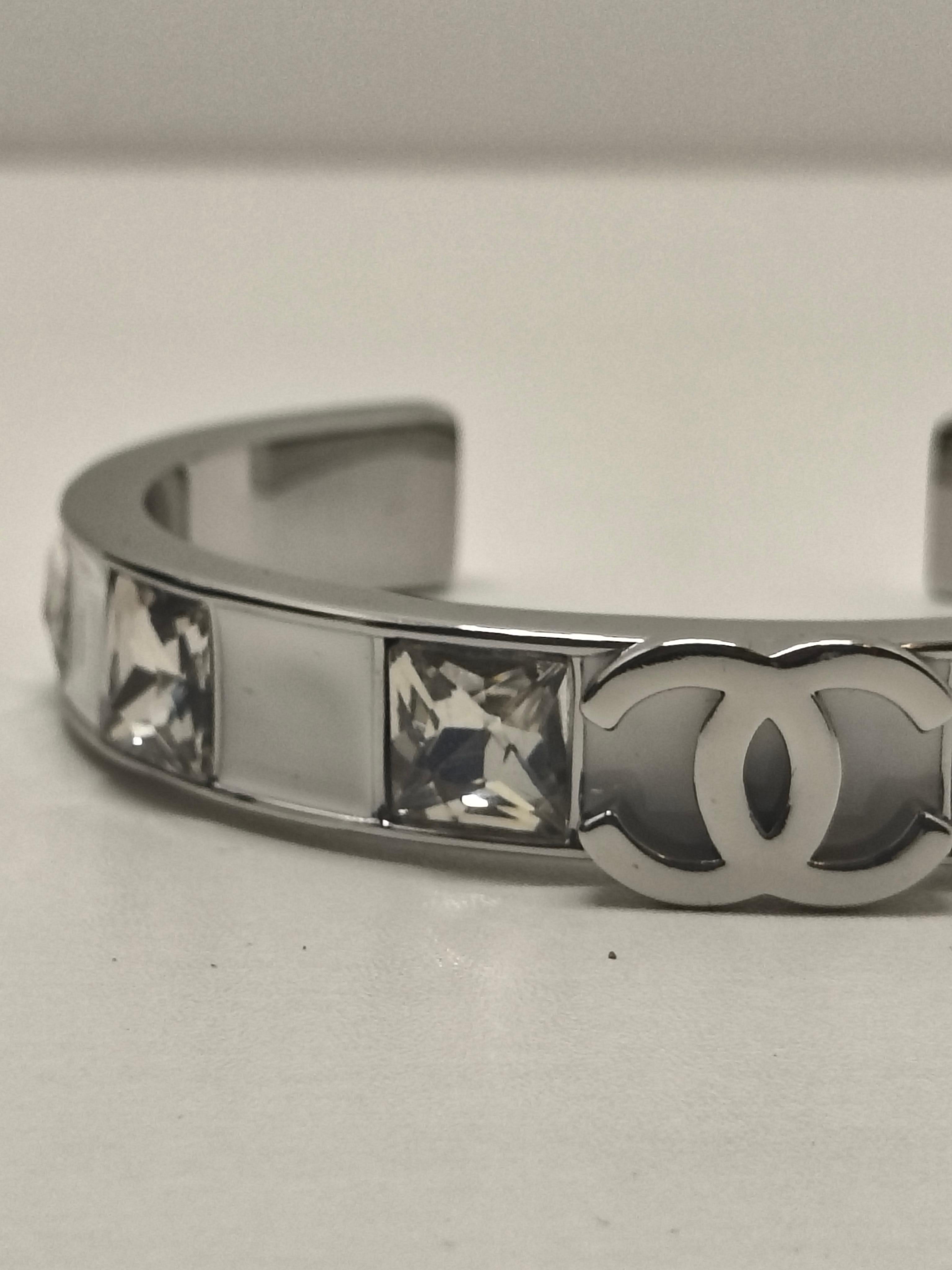 Chanel 24A Weißer emaillierter quadratischer Armreif mit CC-Logo aus Strass

Werten Sie Ihre Schmucksammlung mit diesem auffälligen Chanel-Armreif aus der Herbstkollektion 2024 (24A) auf. Die schlanke, quadratische Silhouette dieses Schmuckstücks