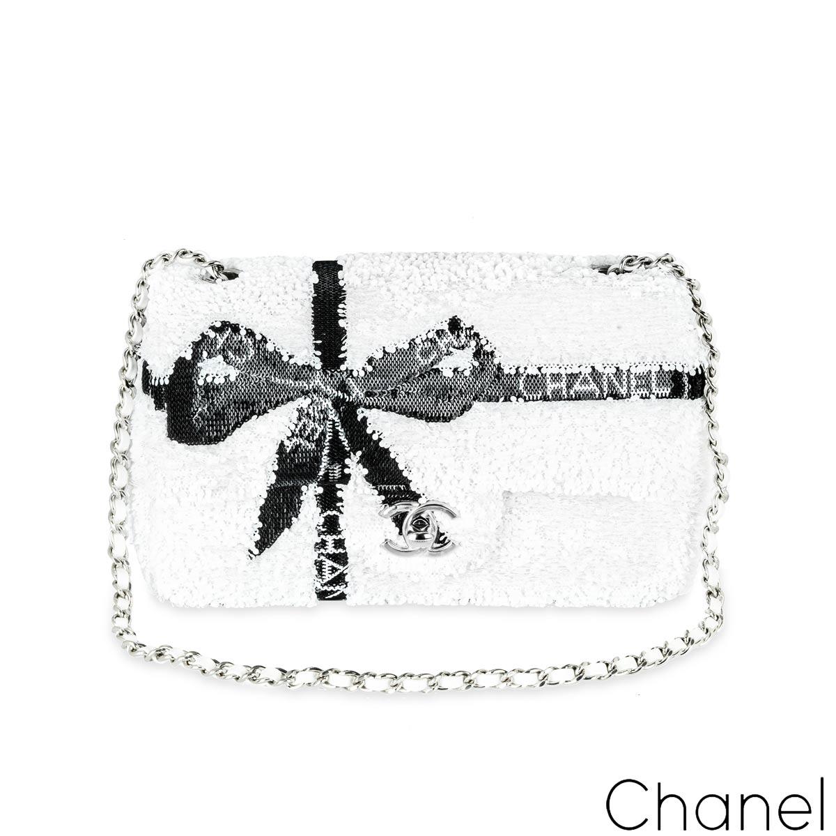 A chic Chanel classic flap mini handbag from Chanel's pre-collection for Fall-Winter 2024. The exterior of this mini flap is crafted in white sequins, featuring a bow created in black sequins with silver-tone hardware. It features a front flap with