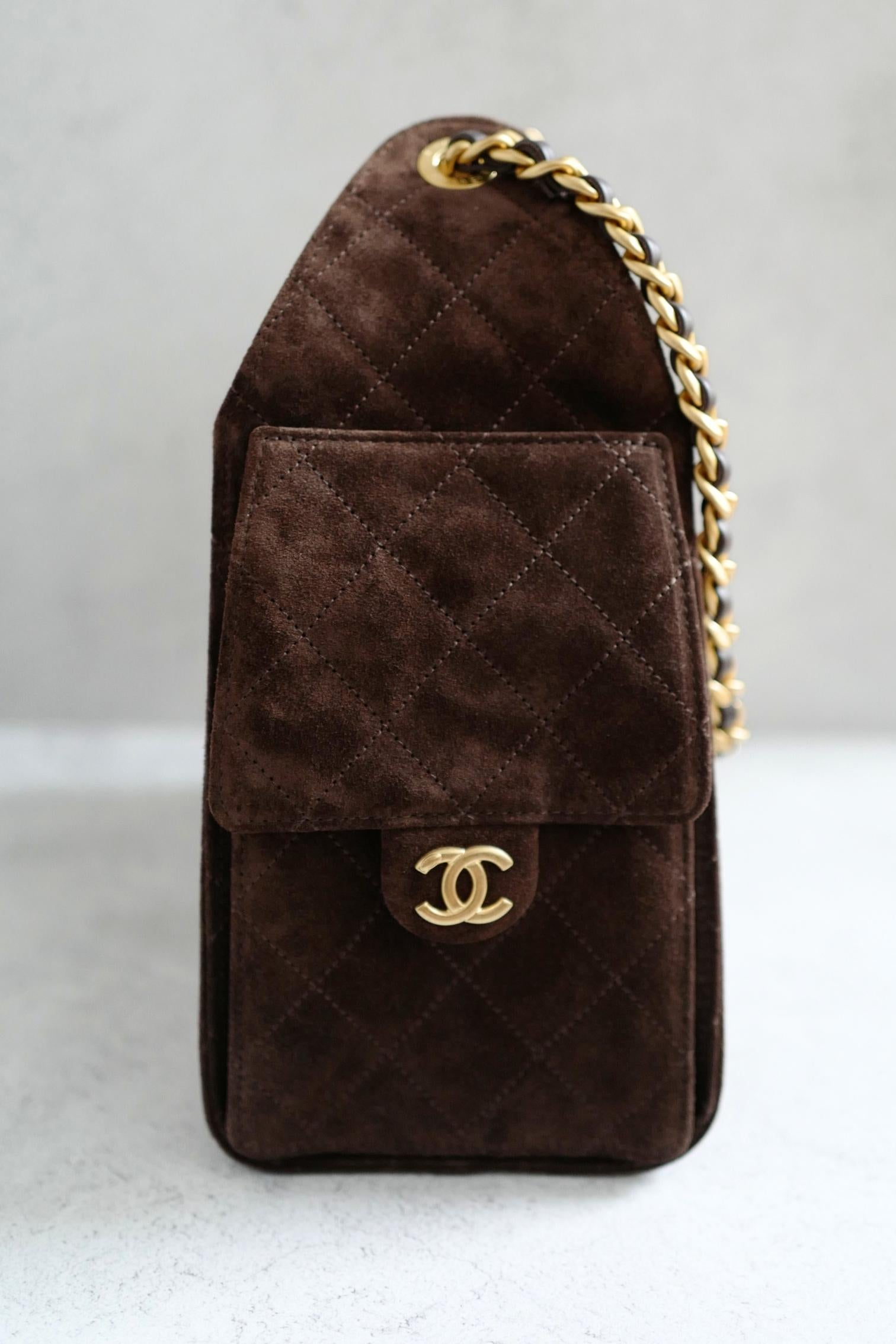 Le petit sac hobo Chanel 25K en daim marron foncé est une pièce intemporelle et contemporaine qui incarne le chic parisien sans effort. Confectionné en cuir velours riche avec le matelassage en losange caractéristique de la marque, ce sac présente