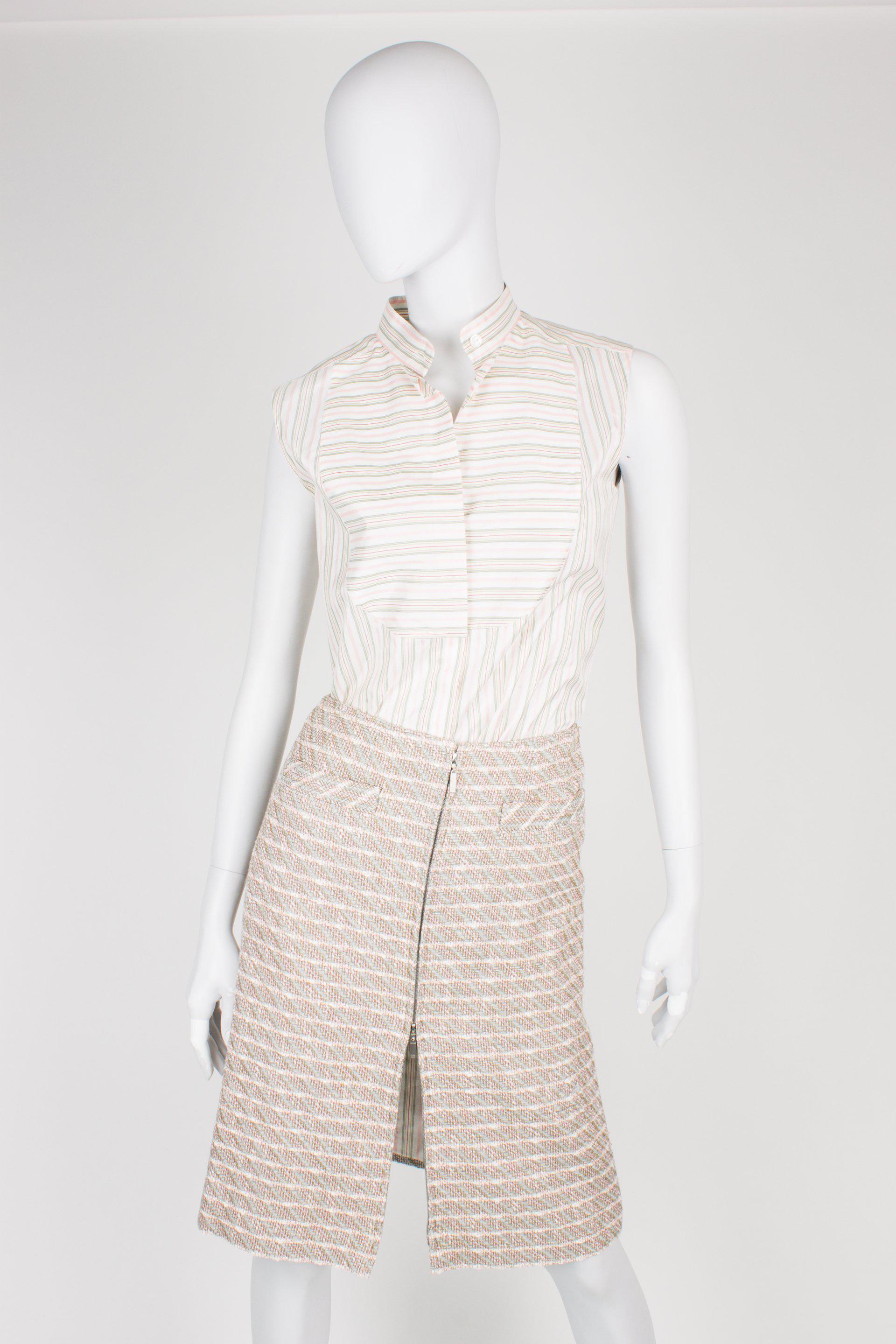 Driedelig pakje van Chanel met een jasje, rokje en blouse in een prachtige kleurencombinatie van groen, grijs, roze en off-white.

Het korte jasje heeft een ronde kraag, geen sluiting en vier opgestikte zakken aan de voorzijde. Onderaan de lange