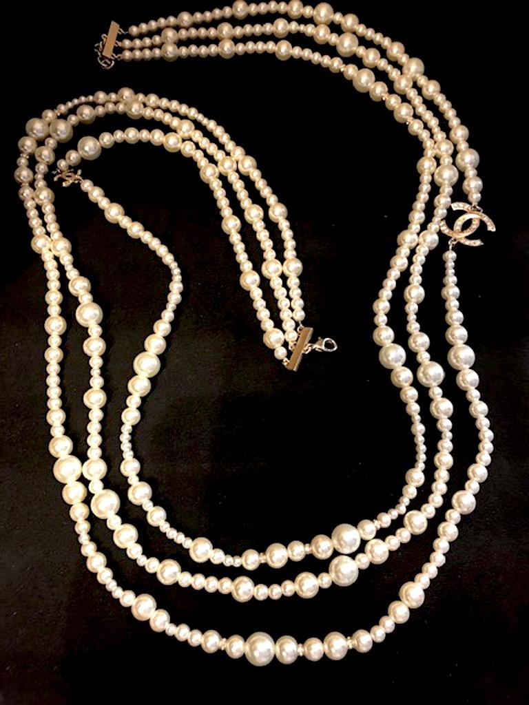 Chanel elegant three strand pearl necklace with rhinestone rondelles and rhinestone CC logo enhancers. Faux pearls have glass interior and are in five sizes of 3, 5, 7, 9 and 11 mm. Two satin gold CC logos. The larger is 1 inch wide and 3/4 inch