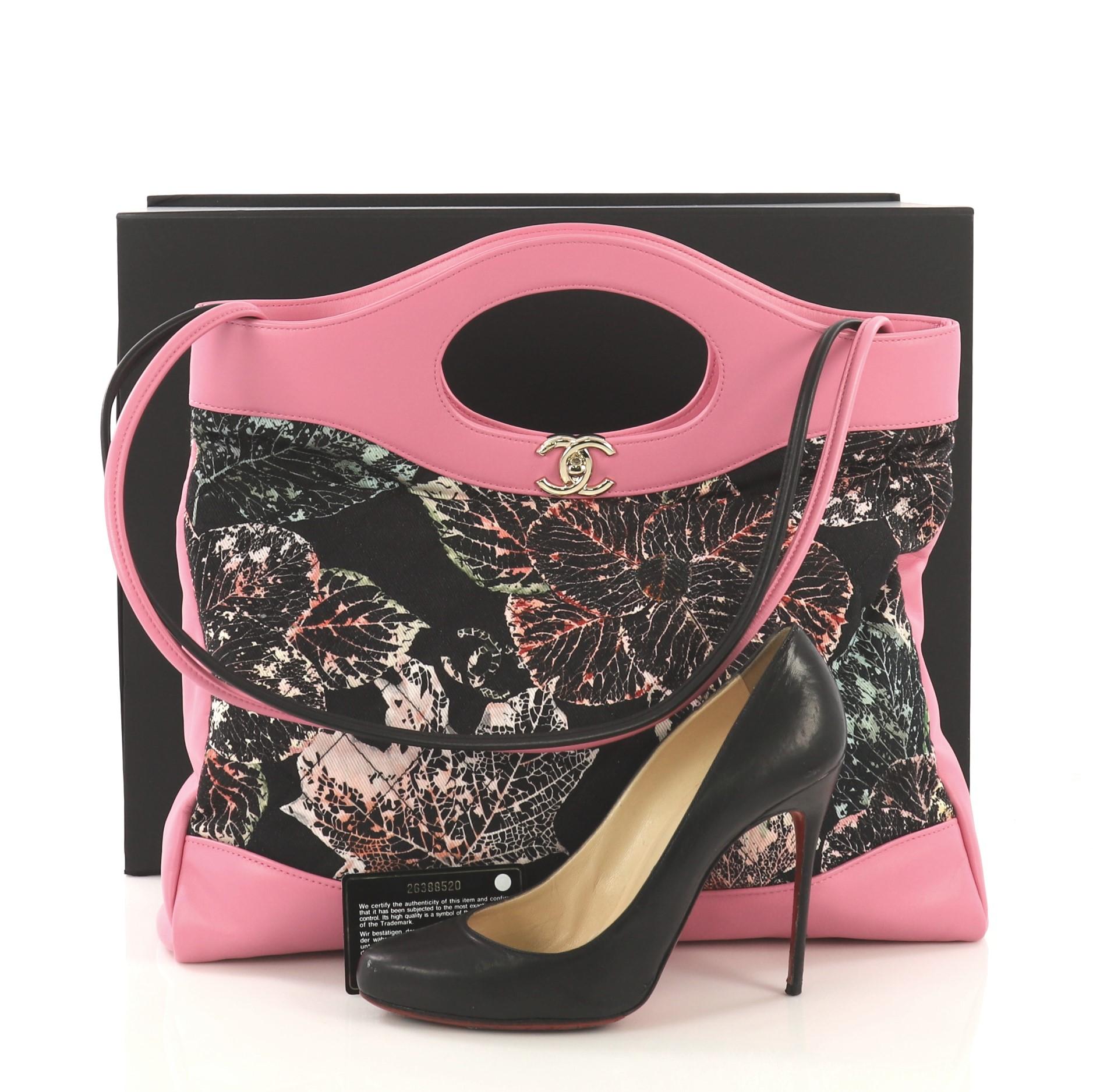 This Chanel 31 Shopping Bag Quilted Printed Cotton and Calfskin Large, crafted in black quilted printed cotton and pink calfskin, features cutout leather handles, slim leather shoulder straps and gold-tone hardware. Its turn-lock closure opens to a