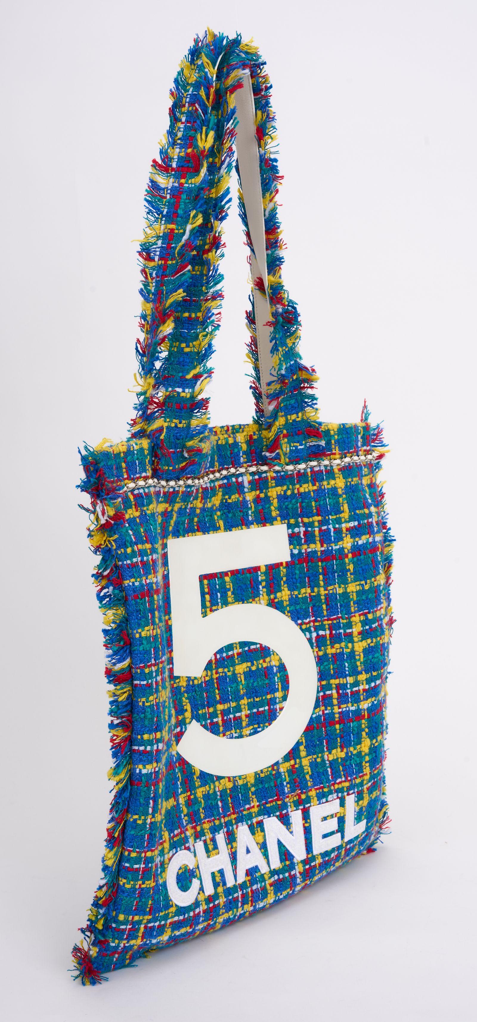This Chanel Tweed N°5 Tote features multicolor tweed with fringe trim and a white CC at the front. It features matching handles, and the top is open to a blue nylon interior with a patch pocket. Comes with hologram, ID card  and generic dust cover. 