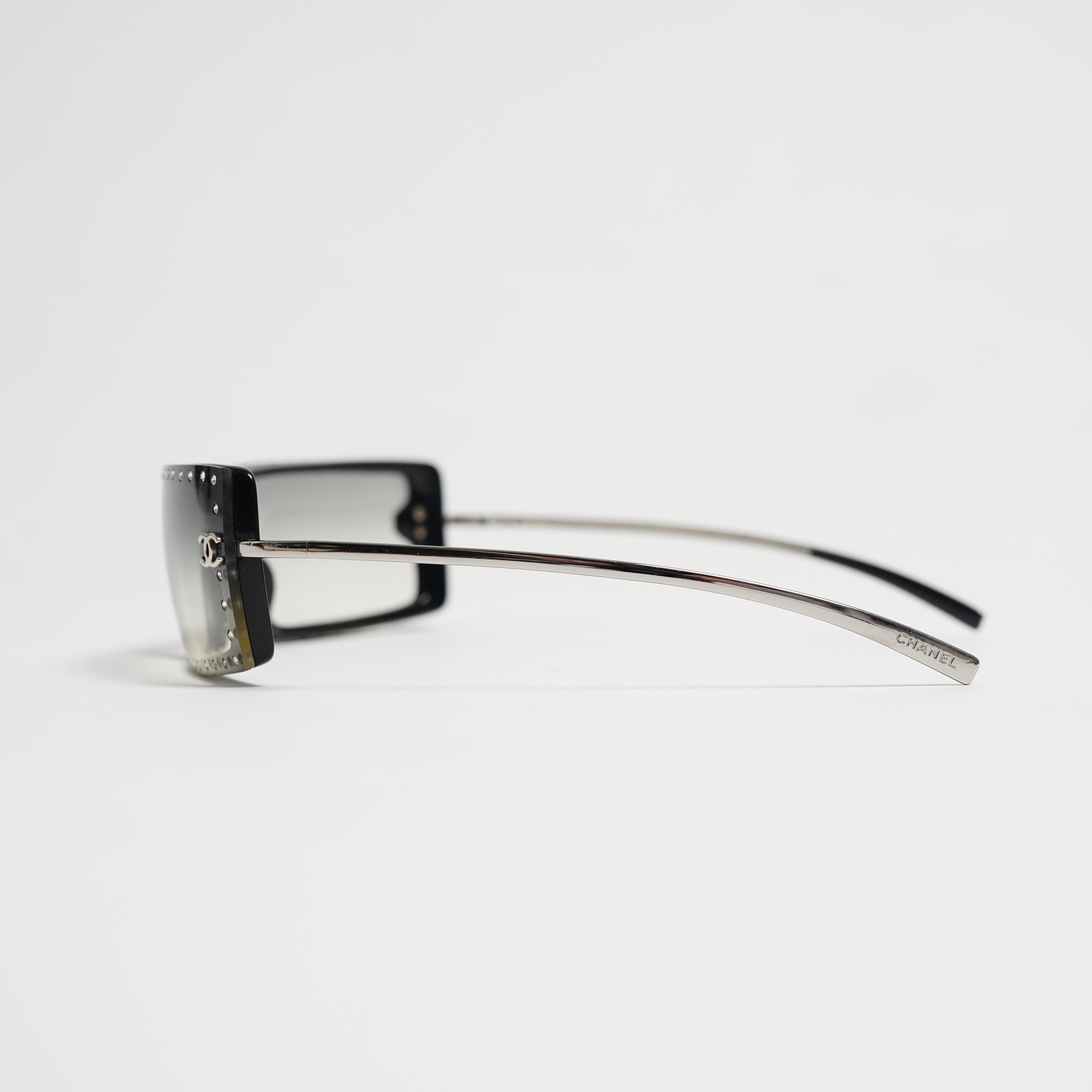 A glamorous and collectible pair of Chanel 5077-B sunglasses, featuring an oversized rectangular rimless design with elegant gradient lenses. The frames are adorned with a full border of sparkling Swarovski crystals, adding a sophisticated,