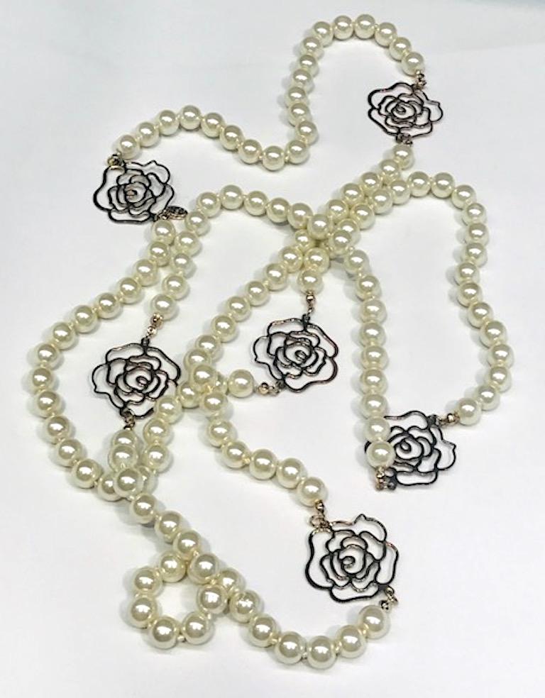 From the Chanel  Autumn 2012 collection is this 63 inch long faux pearl necklace. It has 6 Chanel camelia cutout flower spacers. The faux pearls are individually knotted and and 10 mm 3/8