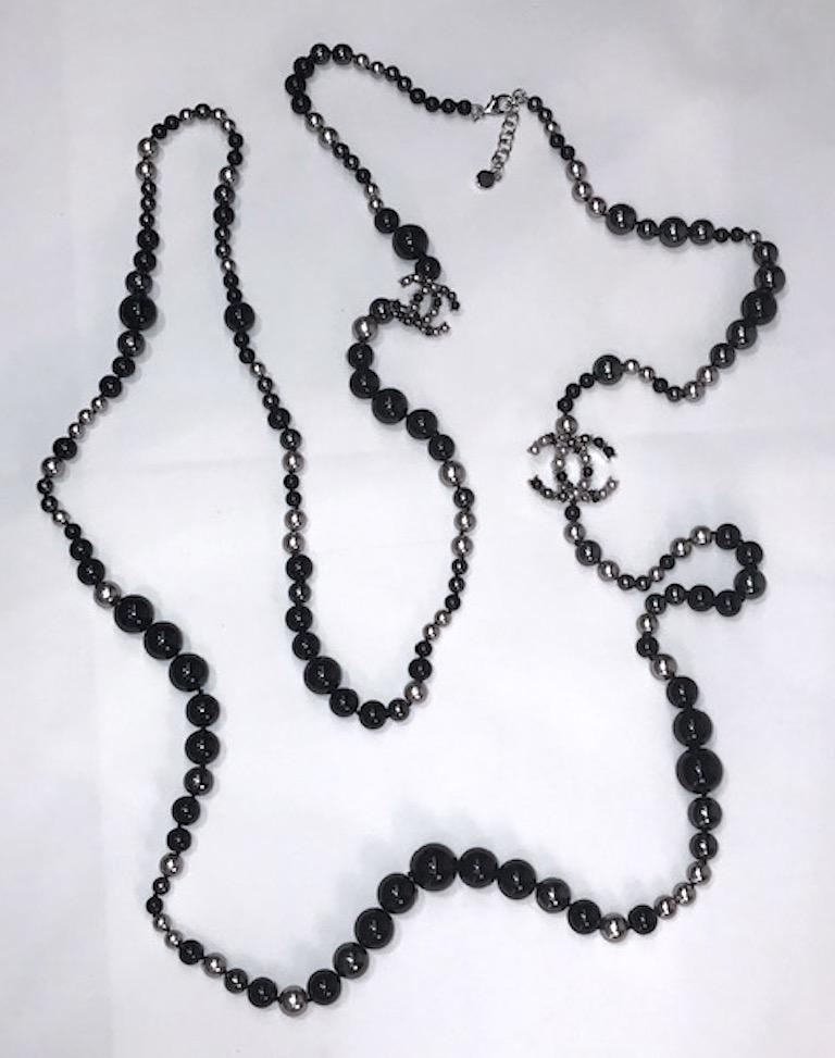 A Chanel striking and chic 72 inch black glass bead and faux silver & grey pearl necklace from the 2018 Vacacion Collection. The beads and pearls are 6, 8, 9, 12 and 14 mm in size. and individually knotted on black thread. Two interlocking CC logos