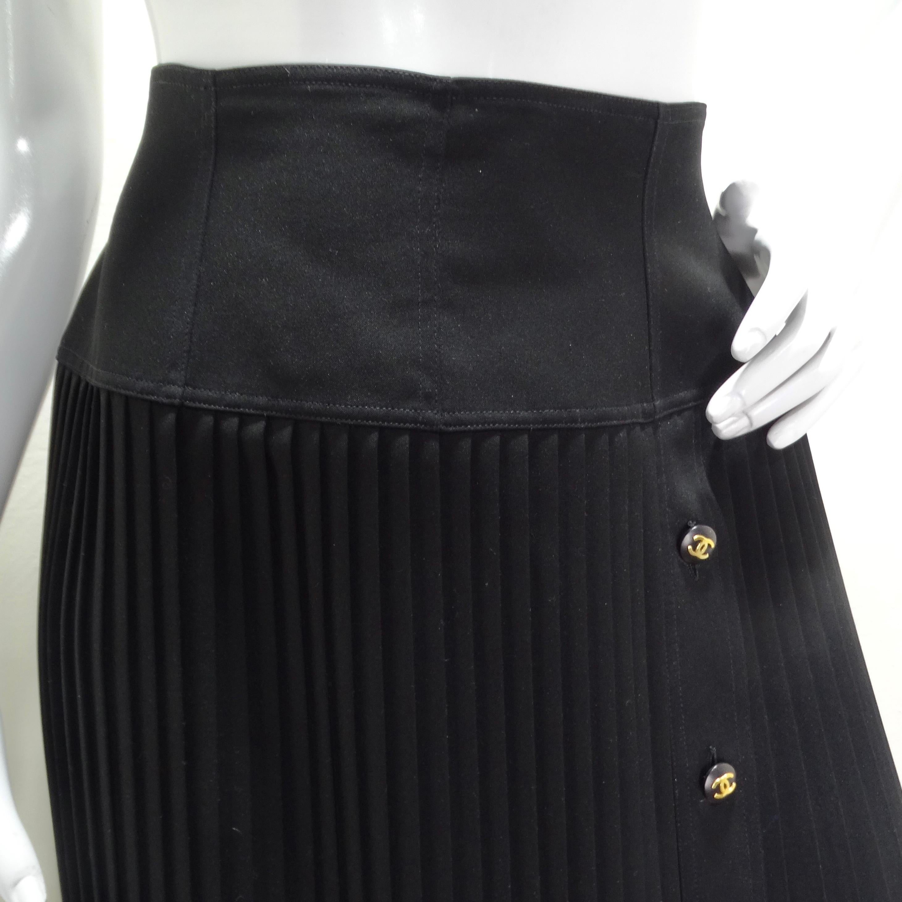Embrace vintage elegance with the Chanel 90s Black Pleated Midi Skirt. This gorgeous skirt boasts a synched waistband, a subtle side zipper, and a flowy mid-length pleated body. Adorned with a row of black buttons featuring the iconic gold-toned
