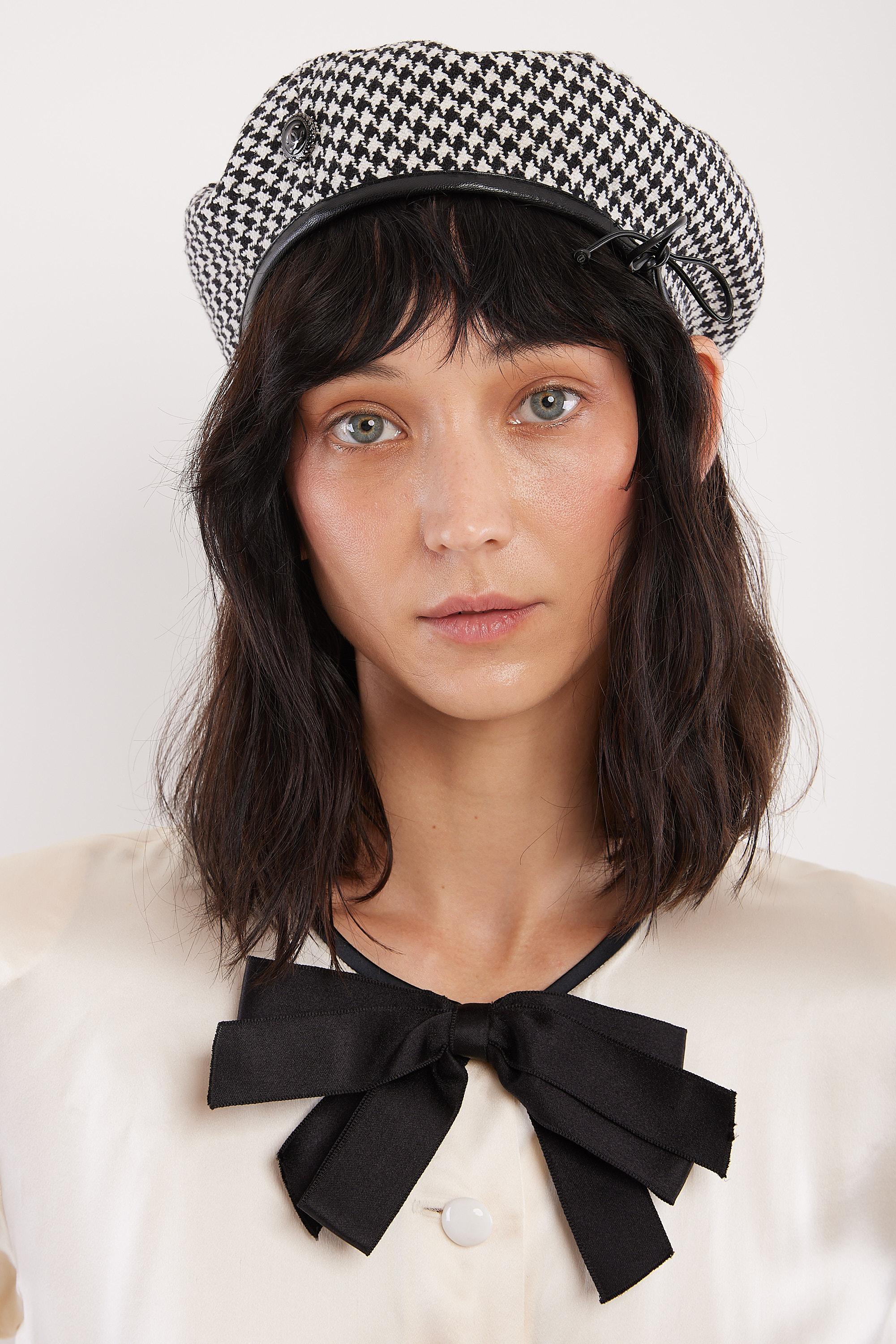 Dating to the 90's, this adorable Chanel beret is made from black & white houndstooth tweed with black leather trim and a silver & black enamel CC metal logo charm. Fully adjustible with the leather side tie, this is a cute & versatile transeasonal