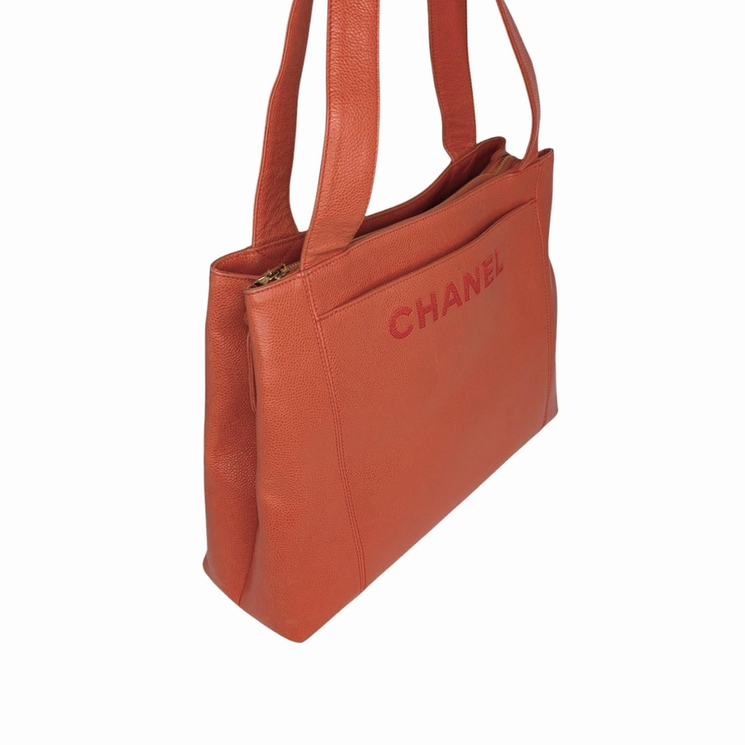 This stunning vintage Chanel tote from Karl Lagerfeld's iconic 1996-1997 collection is a must-have for any fashion enthusiast. Crafted in luxurious orange caviar leather, the bag features a leather Chanel logo zipper pull accented with 24K gold