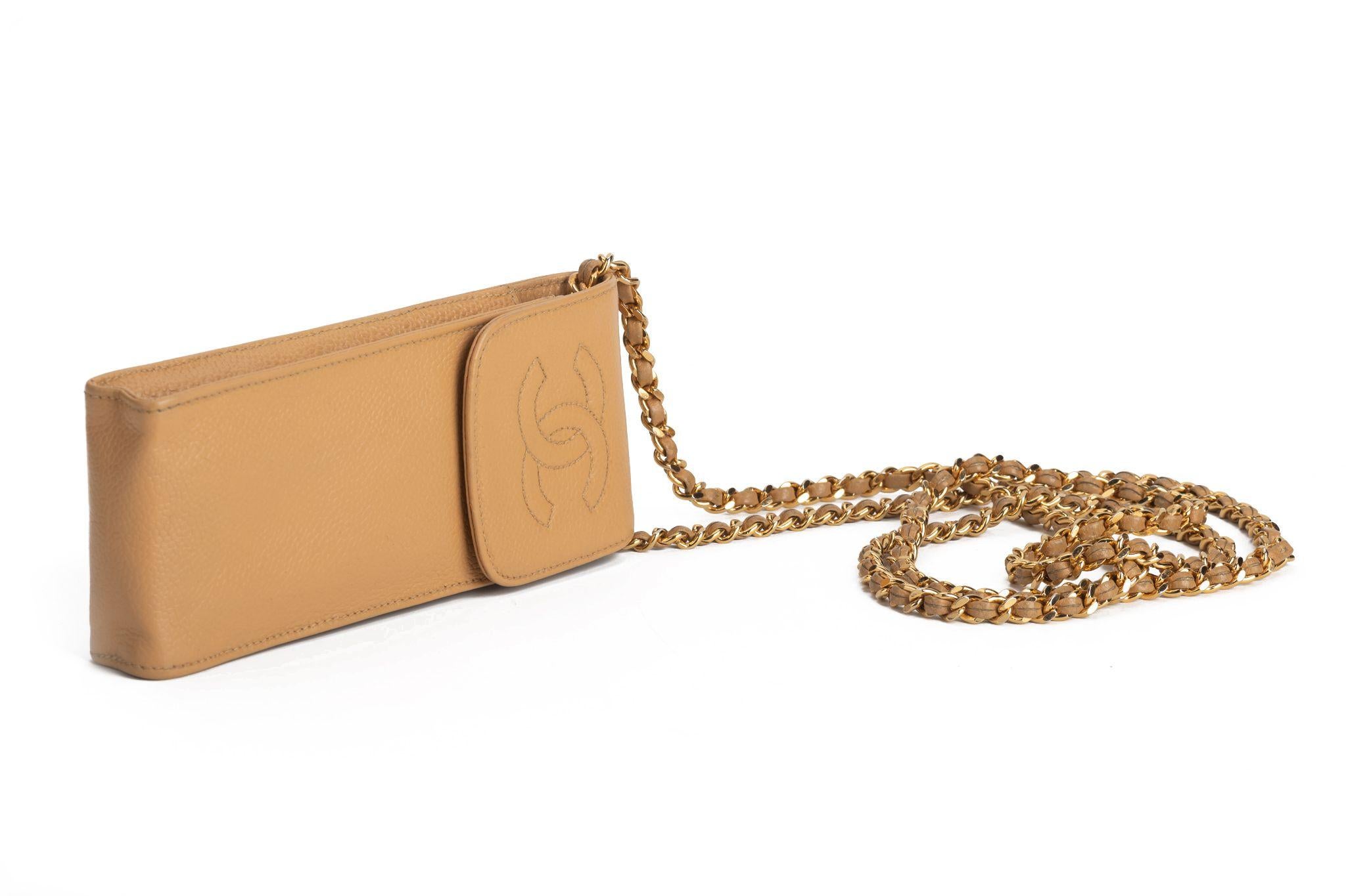 Chanel phone case necklace in beige. The bag is made of calfskin and on front if the flap is the typical CC logo imprinted. The piece comes with a chain and can be worn as a necklace or crossbody bag. It is in excellent condition and comes with a